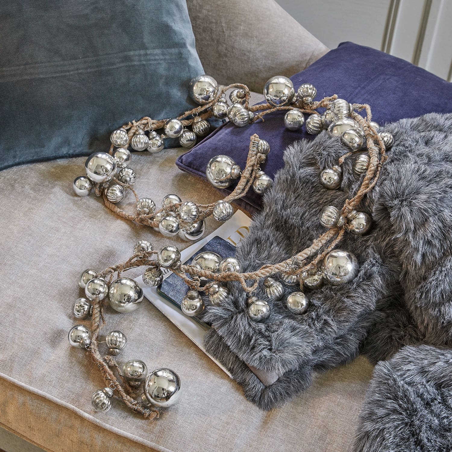 Ghirlanda Pearls Catena decorativa con sfere metalliche argento su corda di lino su divano con cuscini