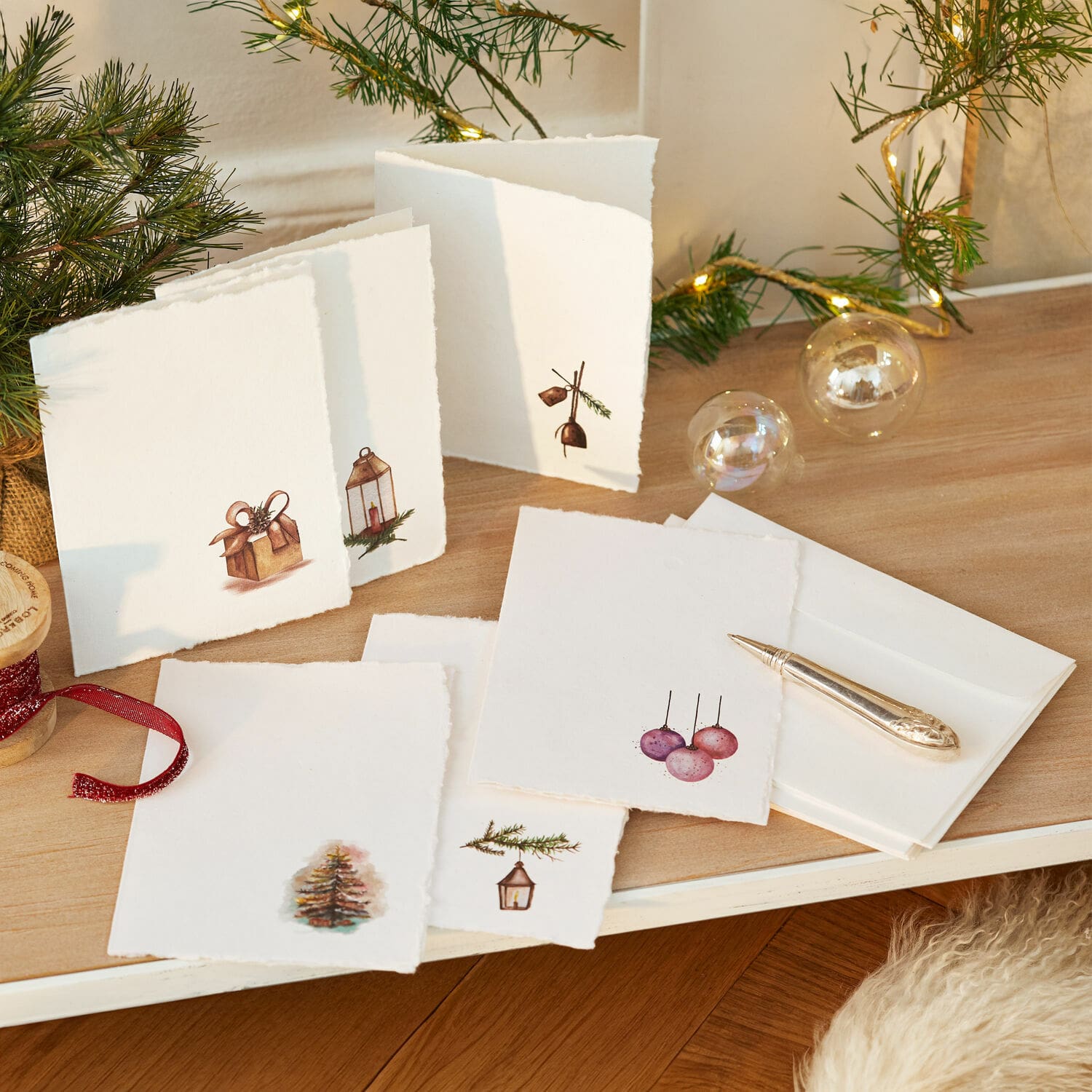 Set di 6 biglietti di auguri Aeloria Set di biglietti natalizi bianchi con motivi di albero e regali su tavolo in legno con luci LED