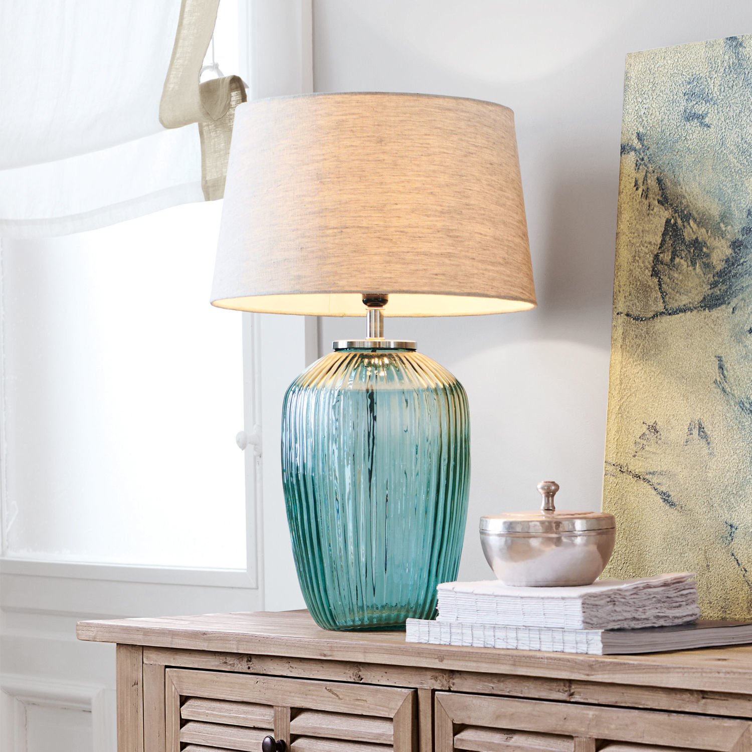 Lampada da tavolo Fenis Lampada da tavolo in vetro verde con paralume beige su mobile in legno chiaro