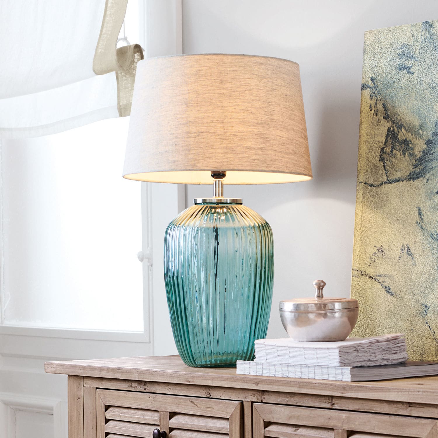 Lampada da tavolo Fenis Lampada da tavolo in vetro verde con paralume beige su mobile in legno chiaro