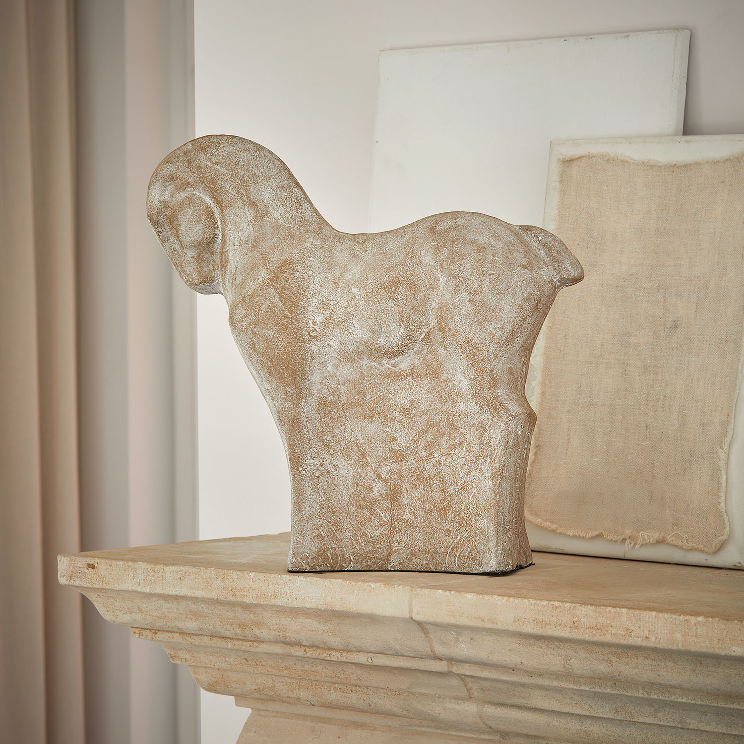Scultura decorativa a forma di cavallo in pietra beige su camino rustico in pietra