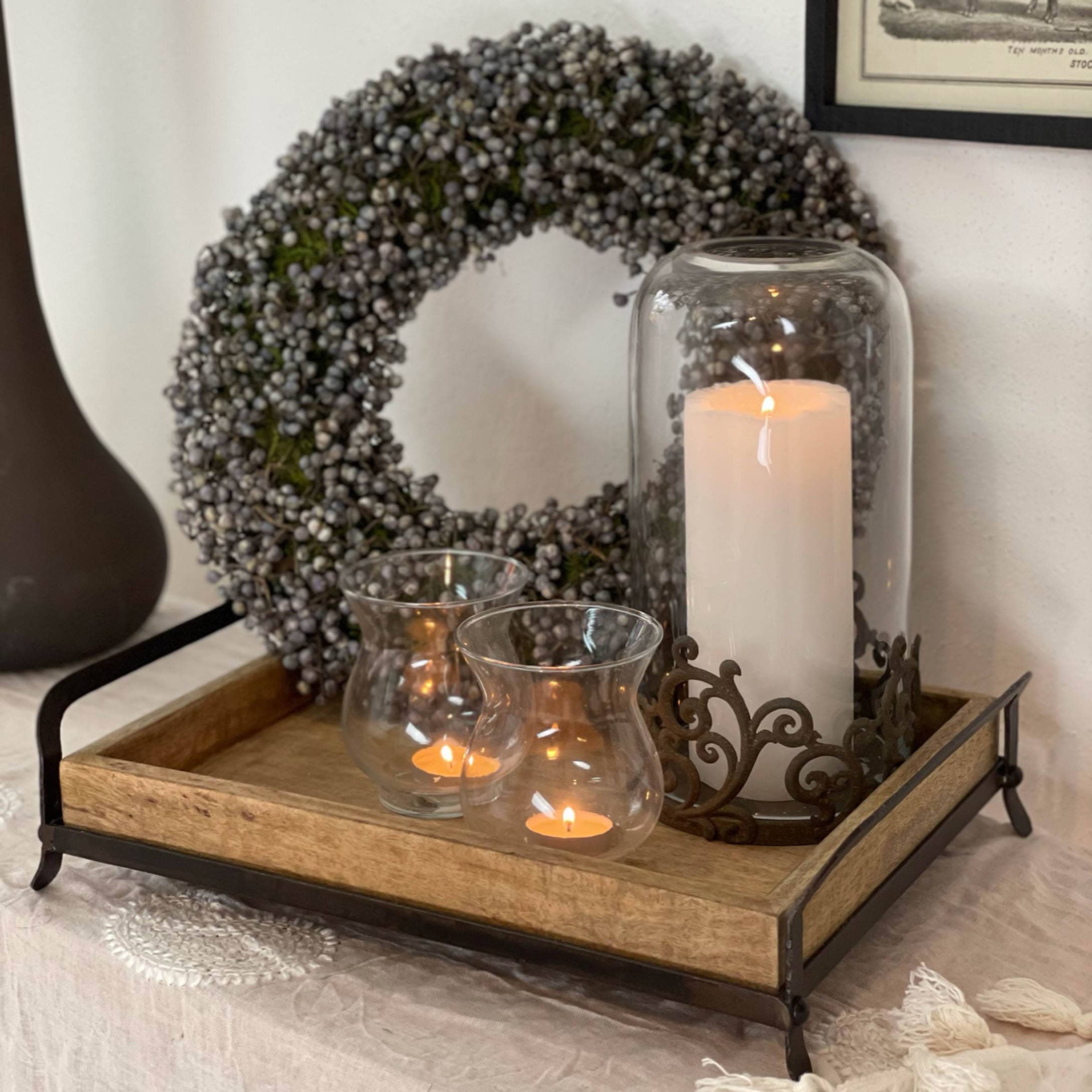 Vassoio in legno con cornice in metallo, candele decorative e corona autunnale con bacche grigie