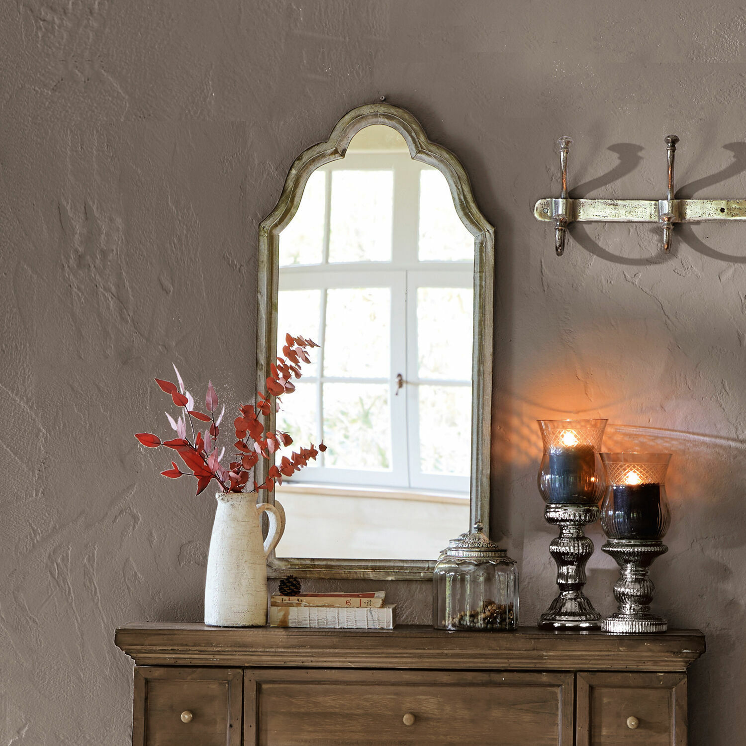 Specchio Libasse Specchio rustico con cornice in legno beige sopra una credenza con decorazioni interne