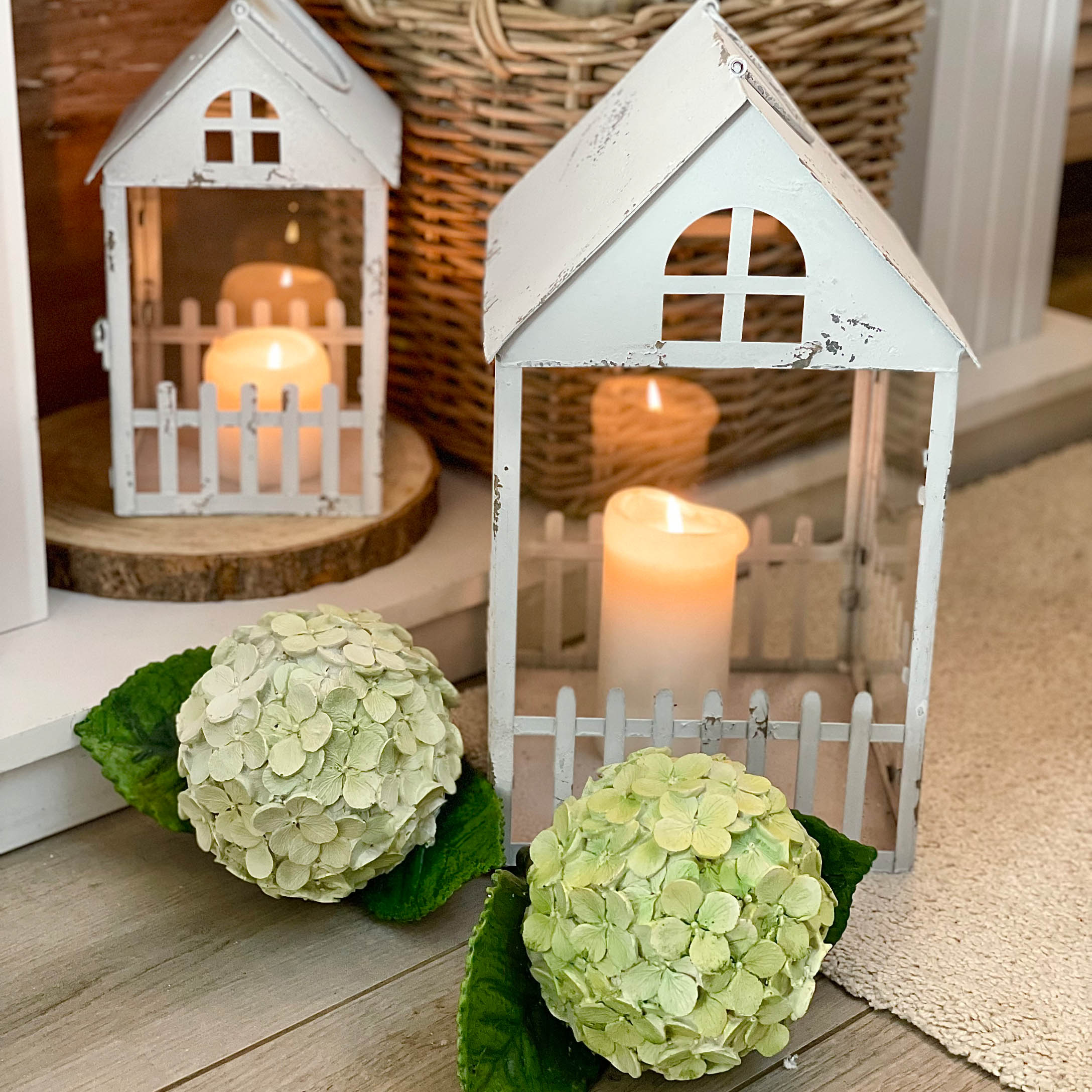 Lanterne in metallo bianco stile rustico con candele accese e decorazione floreale verde