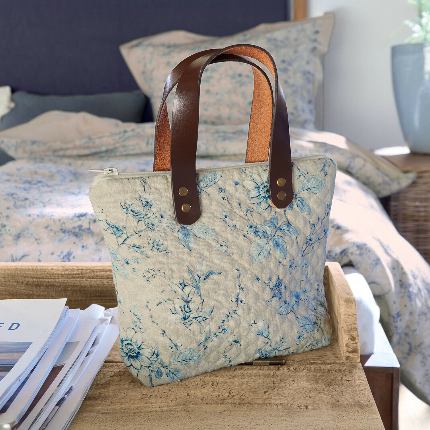 Borsa Vailenne Borsa trapuntata beige con motivo floreale blu e manici in pelle marrone su tavolo in legno