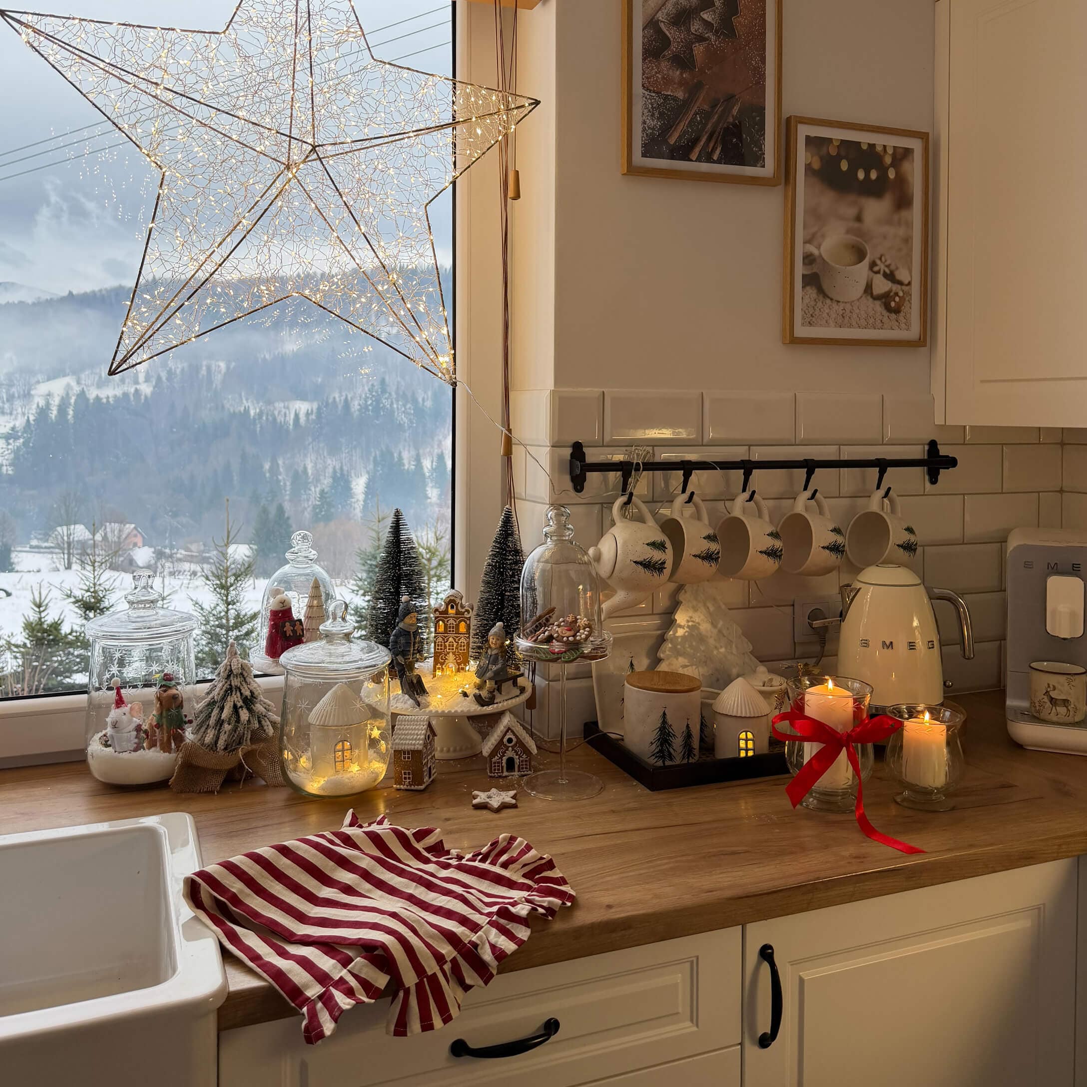 Cucina con piano in legno decorata per Natale, tazze bianche con motivo albero e luci LED