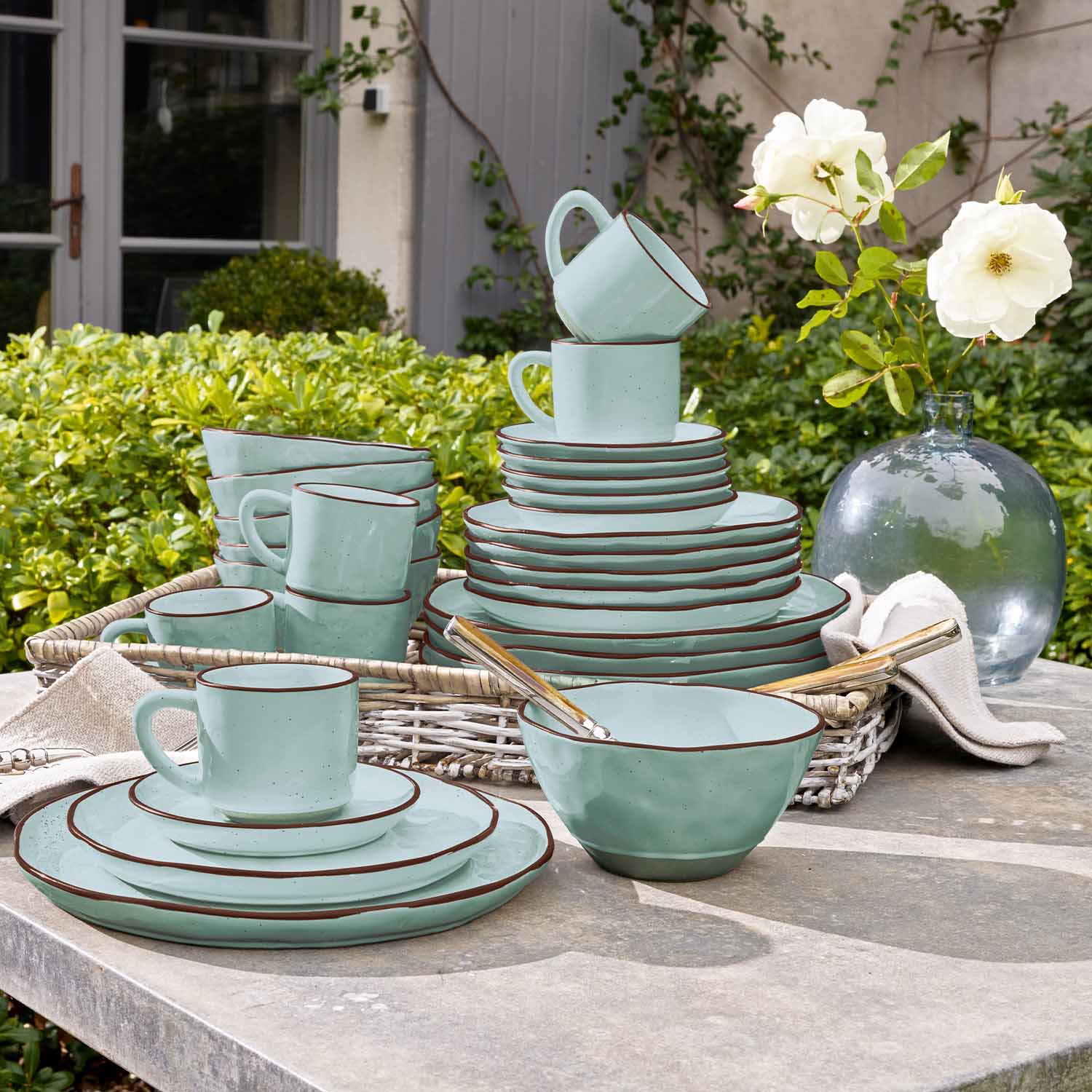 Set di stoviglie in ceramica verde menta con bordo marrone su tavolo da giardino