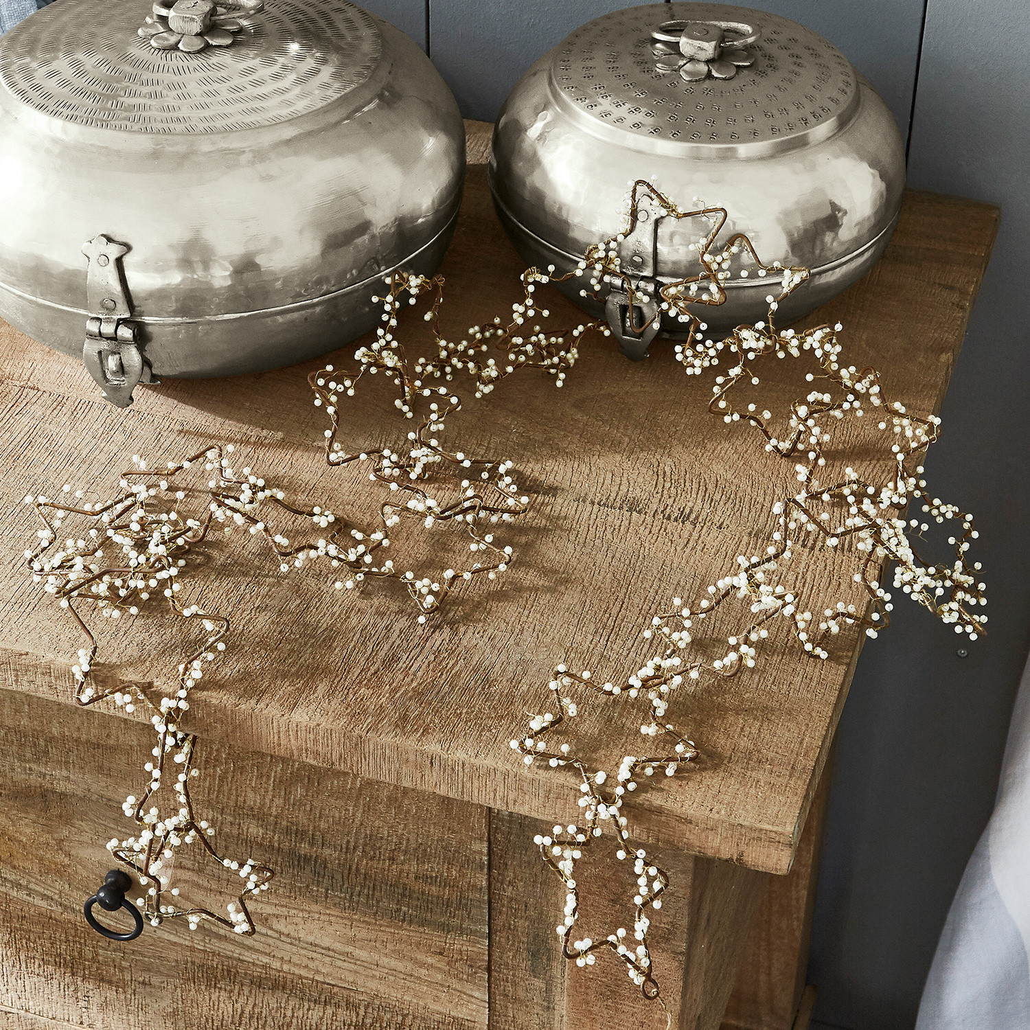 Festone Ariane Ghirlanda decorativa a forma di stelle con perle bianche su tavolo in legno, decorazione natalizia