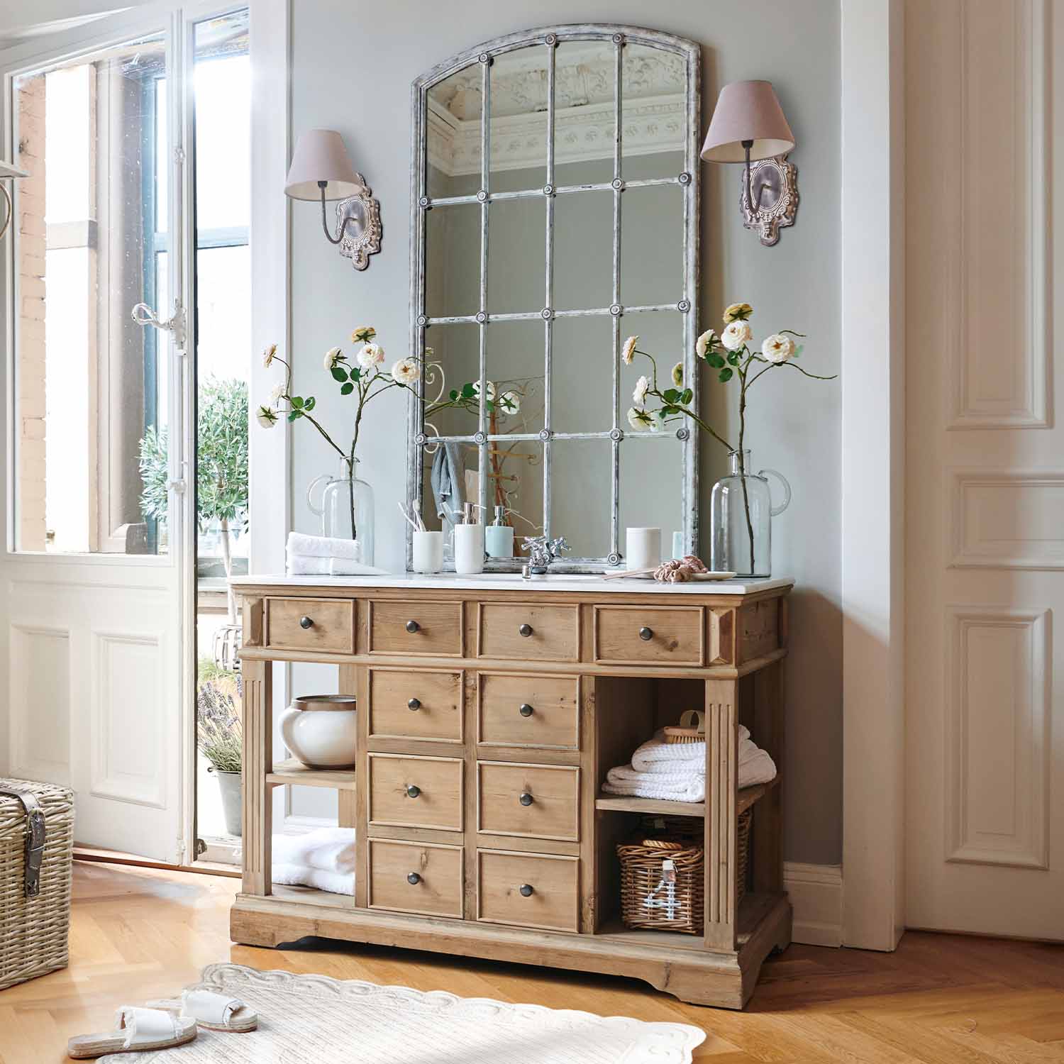 Cassettiera in legno naturale con molti cassetti e grande specchio vintage in tonalità chiara