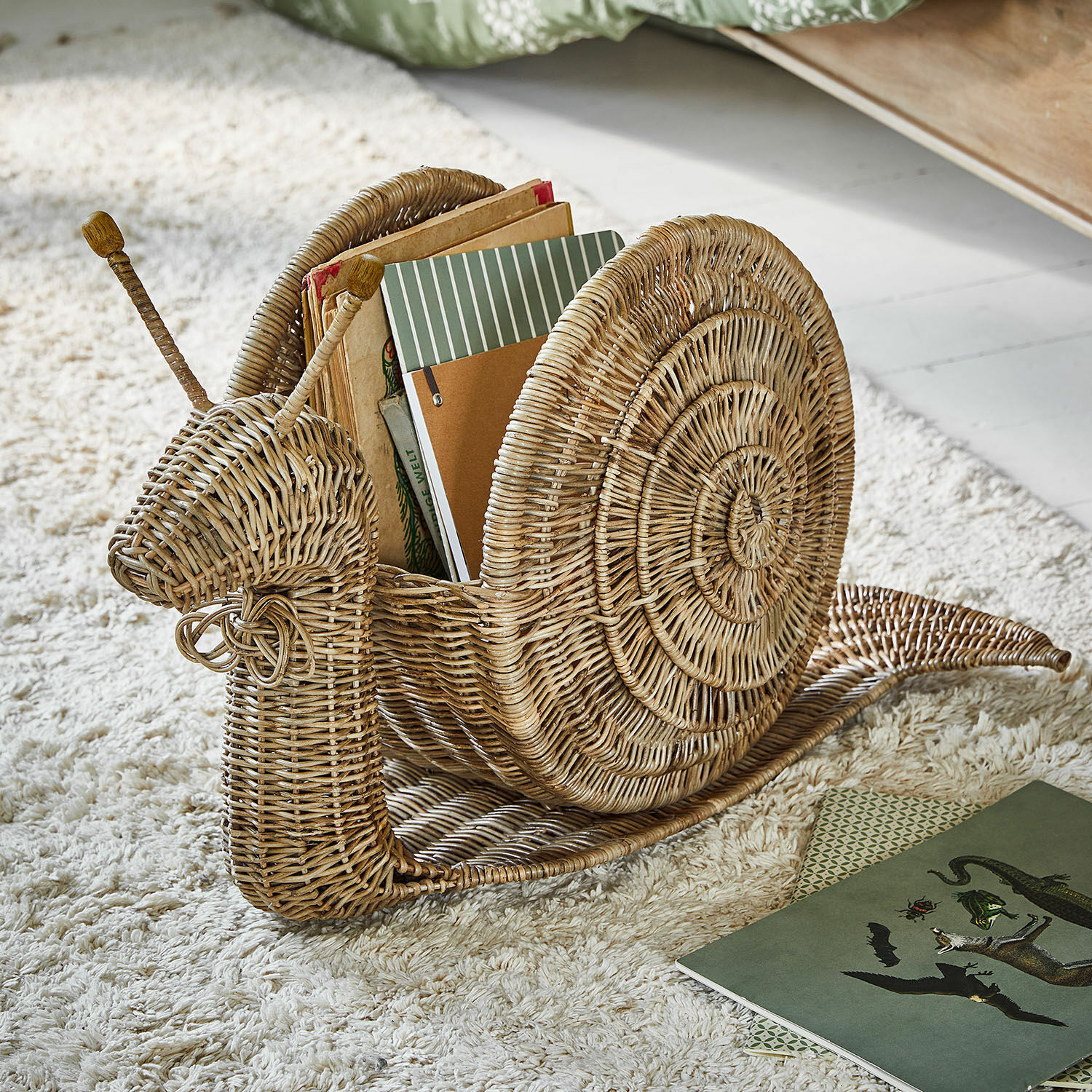 Cesto Tigrelle Porta libri a forma di lumaca in vimini naturale su tappeto chiaro per arredamento casa