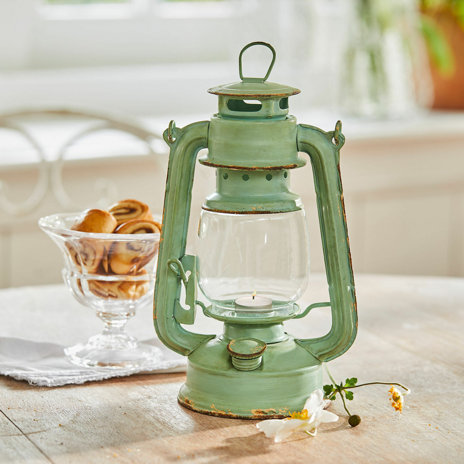 Lanterna Clemence Lanterna in metallo verde effetto invecchiato su tavolo in legno con dolci sullo sfondo
