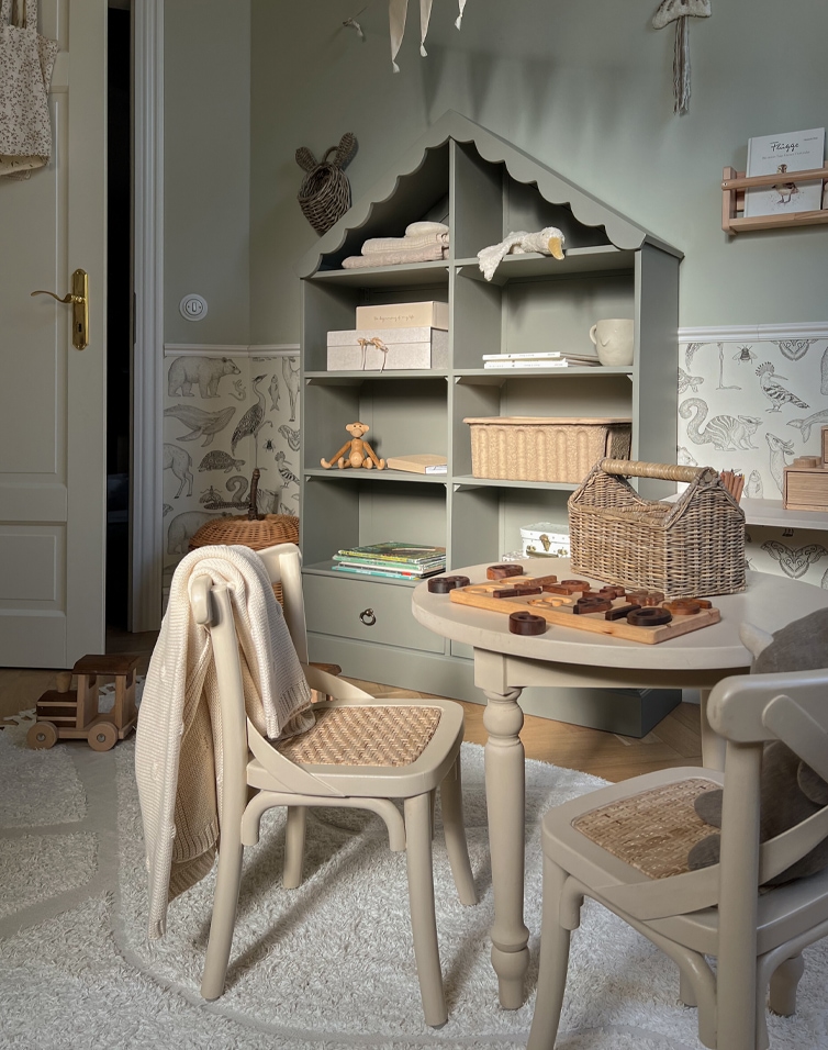 Camera per bambini con scaffale grigio a forma di casa e sedie beige con seduta intrecciata