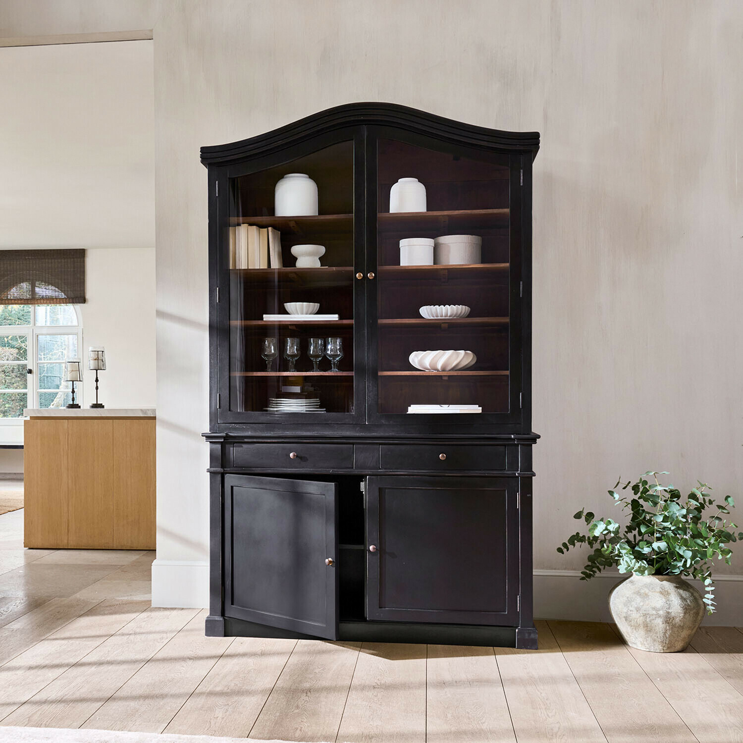 Credenza Westridge Vetrina in legno nero con ante in vetro e scaffali con ceramiche bianche e bicchieri nel soggiorno
