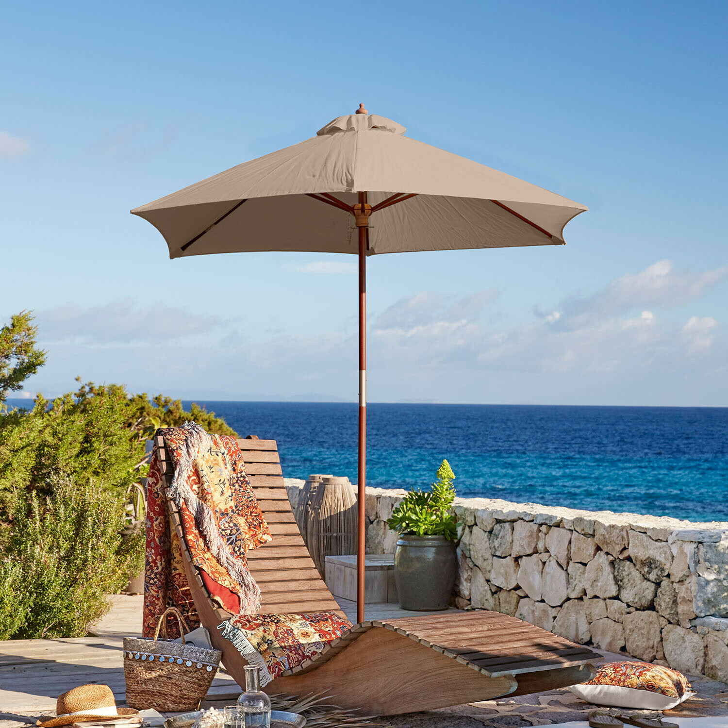 Ombrellone Enfield Lettino in legno con ombrellone beige e coperta colorata vicino al mare, mobili da terrazza