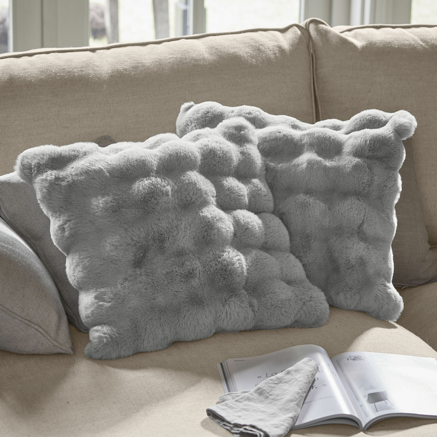 Coppia di copricuscini Zalina Morbidi cuscini decorativi grigi in pelliccia sintetica su divano beige, ideali per il soggiorno