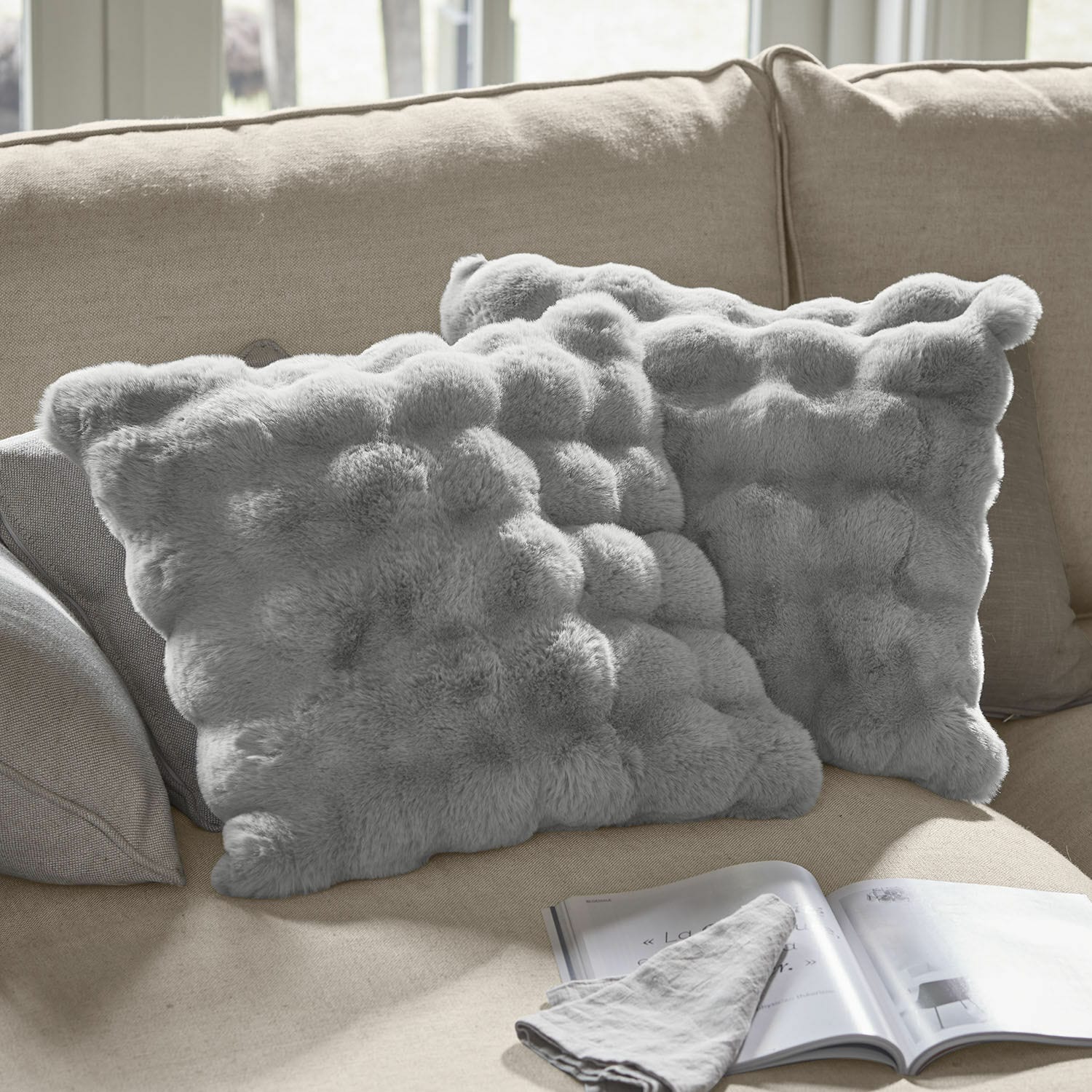 Coppia di copricuscini Zalina Morbidi cuscini decorativi grigi in pelliccia sintetica su divano beige, ideali per il soggiorno
