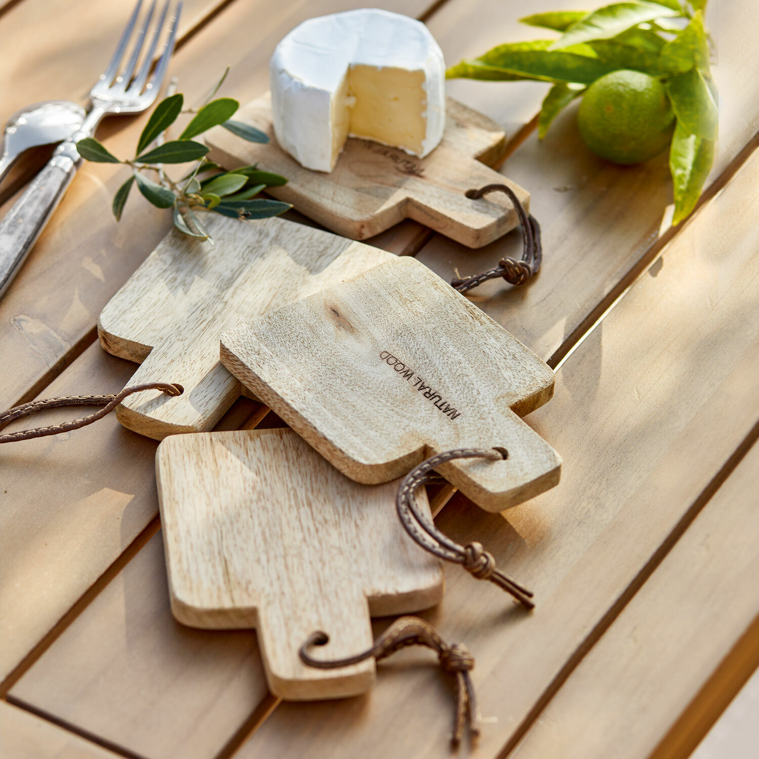 Set di 4 taglieri Boise Set di taglieri in legno naturale con manici e cordini su tavolo con formaggio e lime