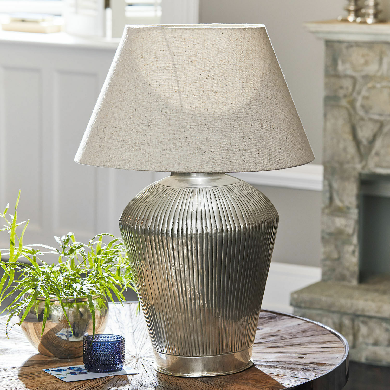Lampada da tavolo Caulières Lampada da tavolo con base in metallo e paralume beige su tavolo in legno in soggiorno