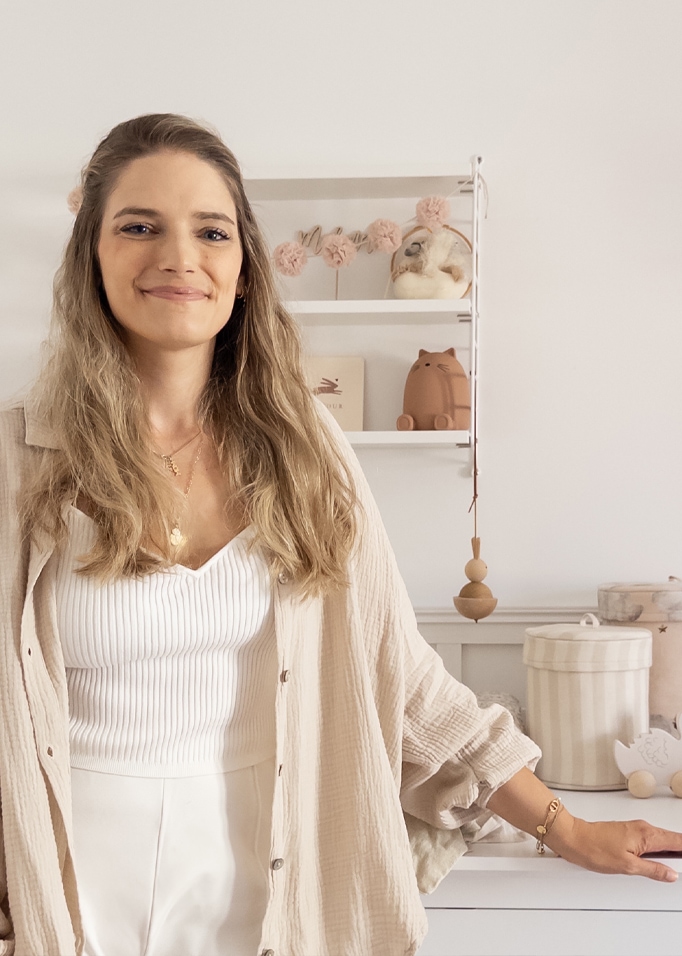Donna sorridente con camicia beige e top bianco in stanza luminosa con decorazioni per bambini