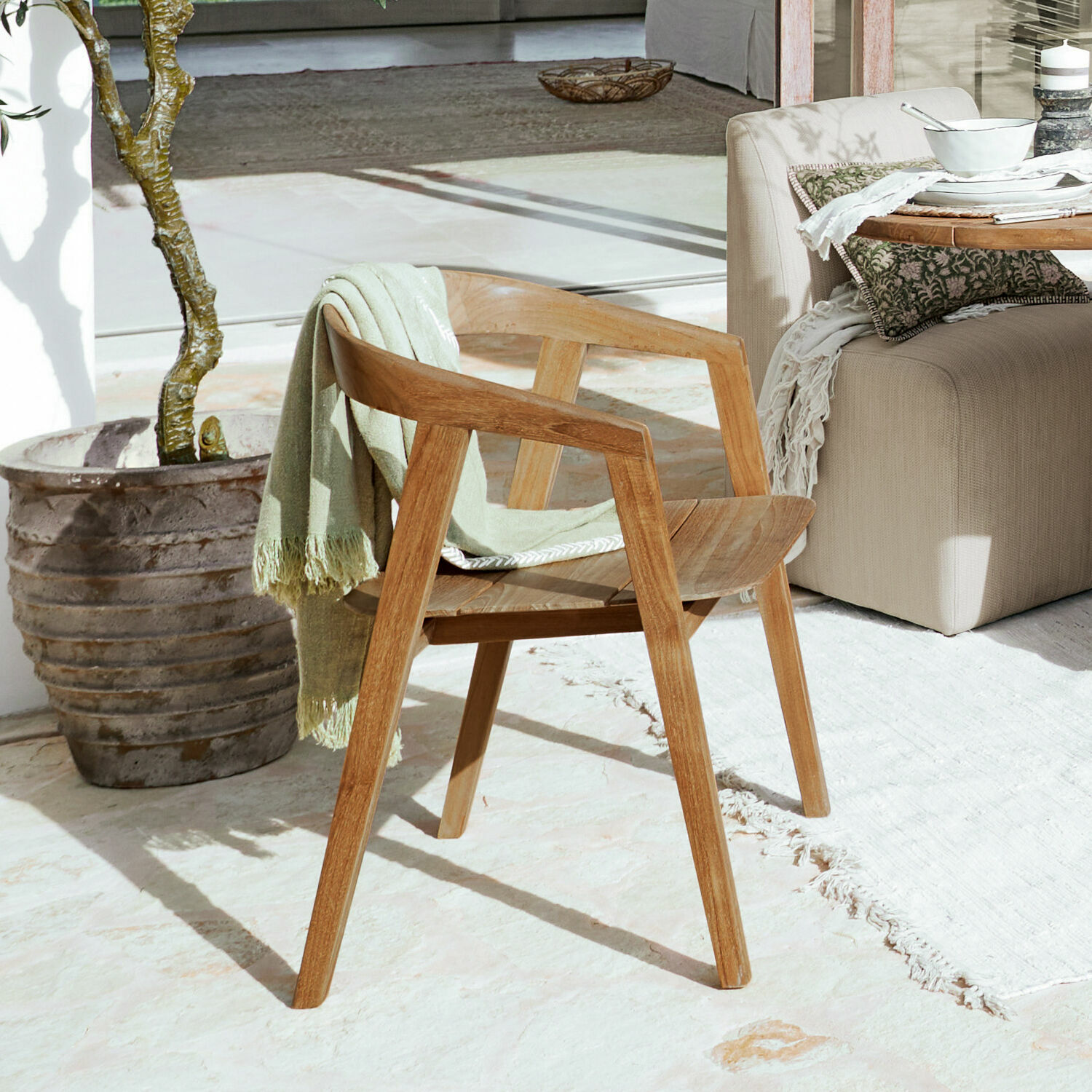 Sedia Saulny Sedia in legno naturale con braccioli e coperta verde su terrazza soleggiata