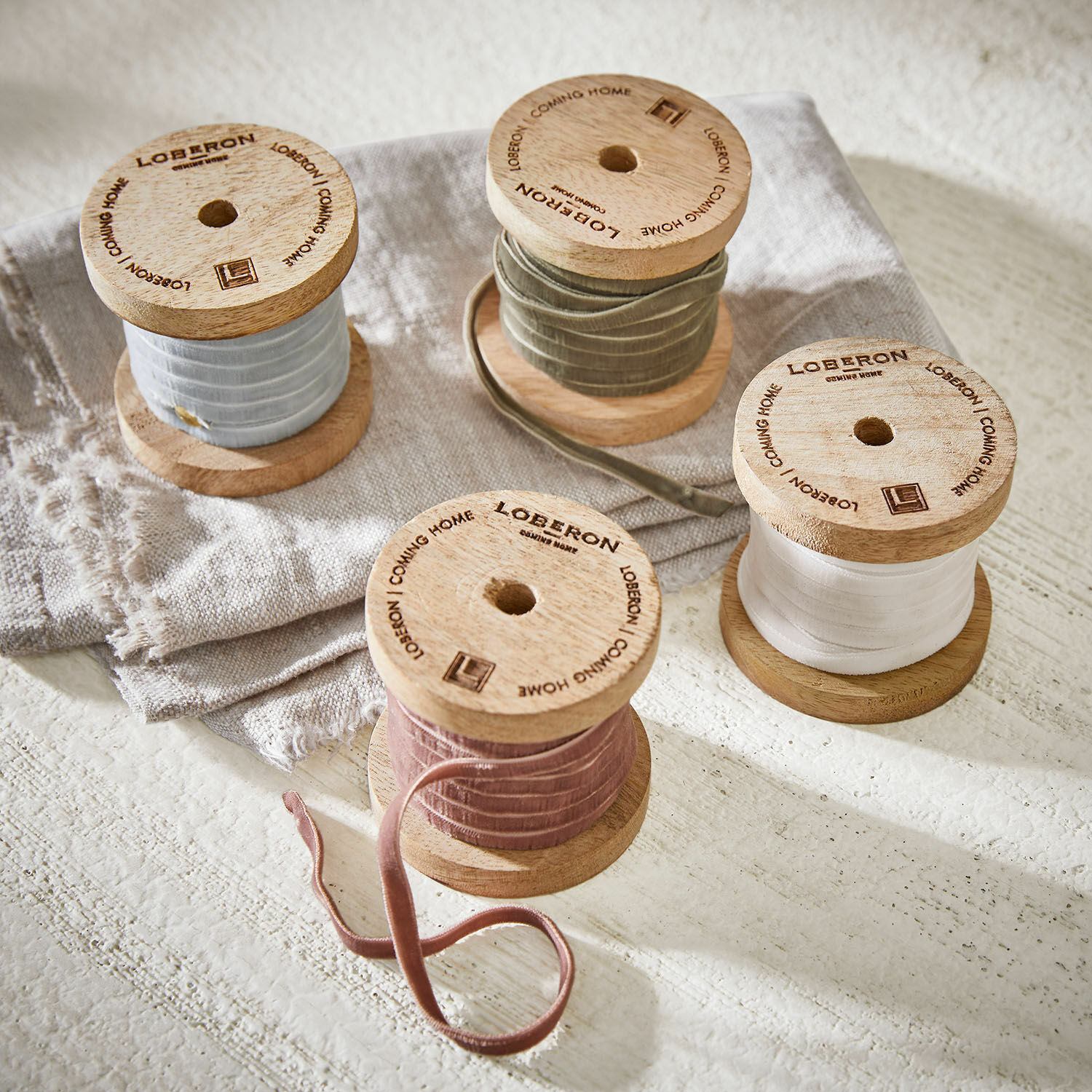 Set di 4 nastri di velluto Hilary Bobine in legno con nastri di velluto color pastello su tessuto di lino, decorazione per interni