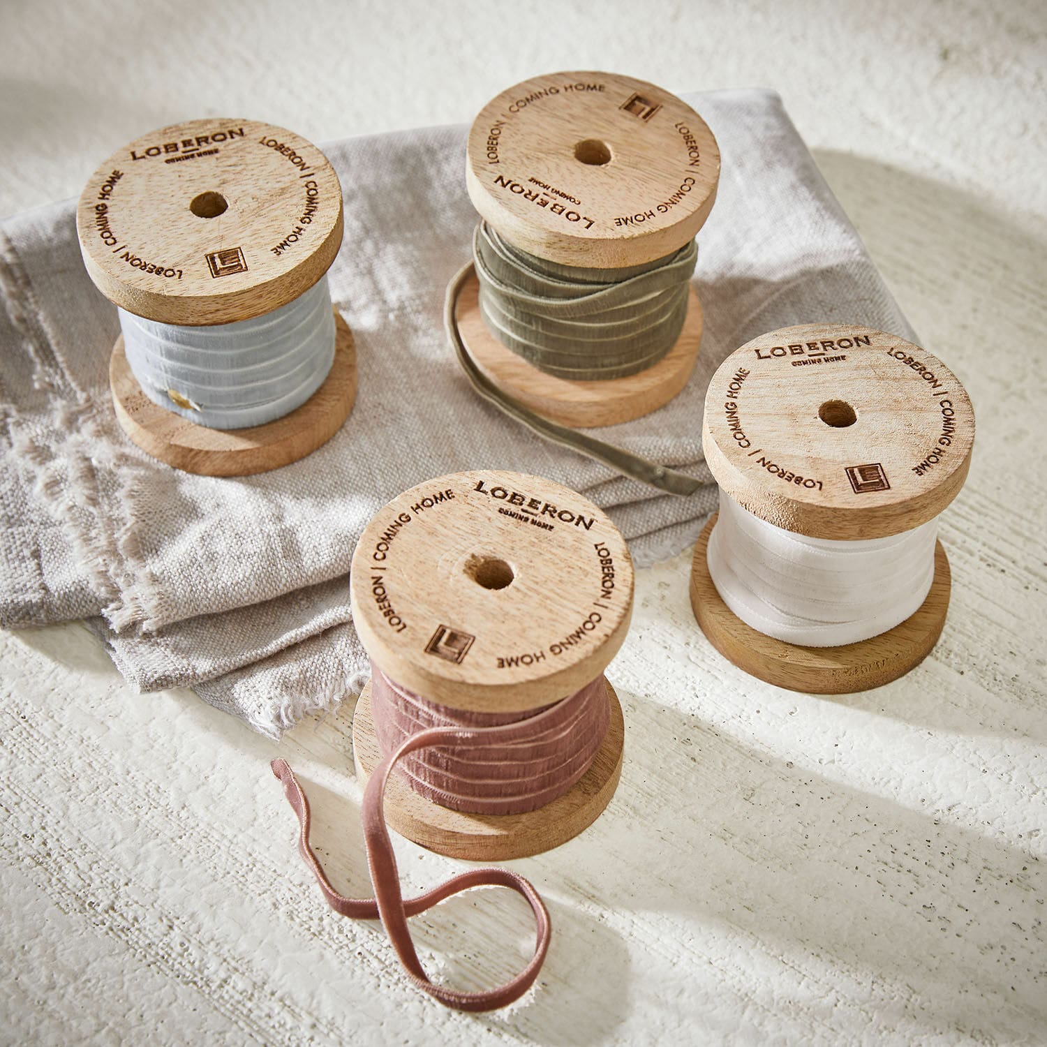 Set di 4 nastri di velluto Hilary Bobine in legno con nastri di velluto color pastello su tessuto di lino, decorazione per interni