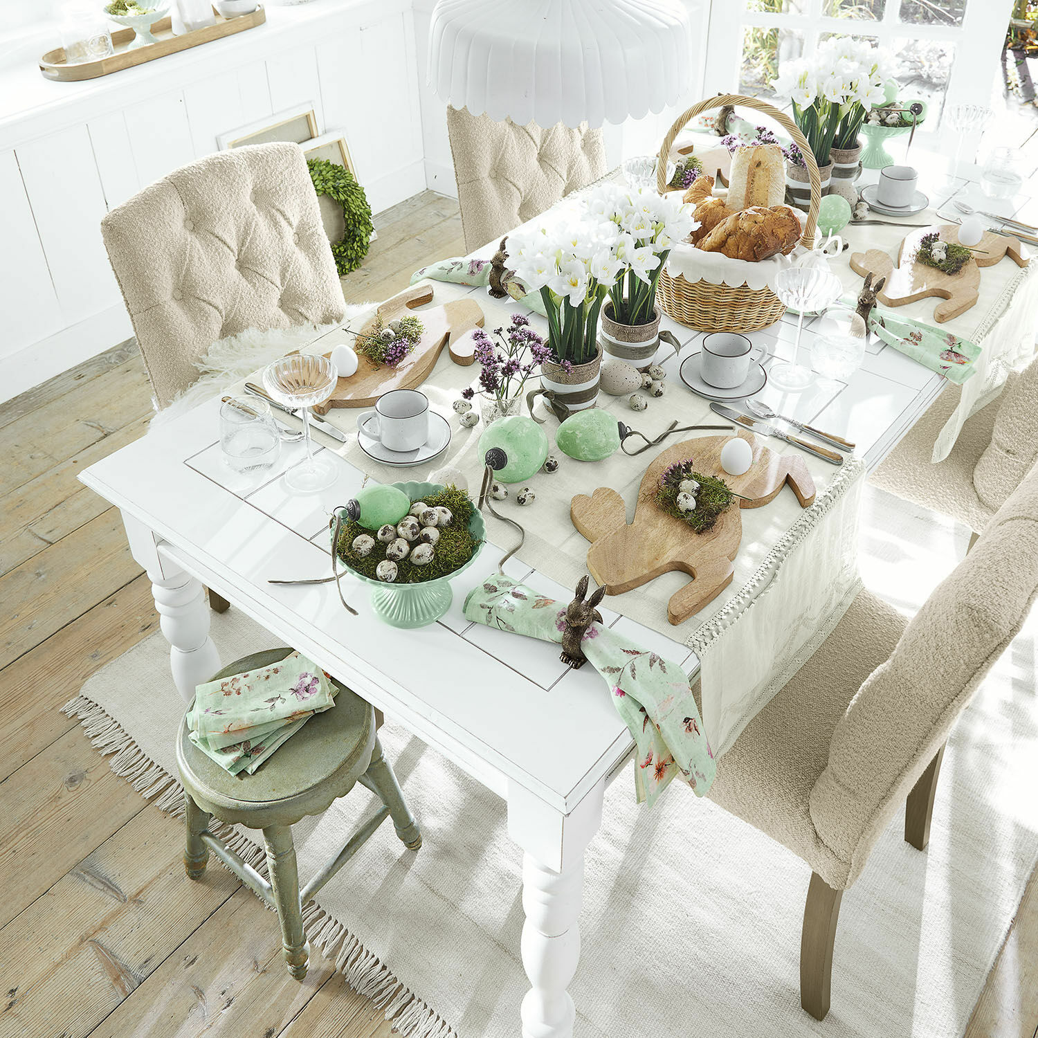 Tavolo Thurleigh Tavolo chiaro decorato per Pasqua con taglieri in legno e accenti verdi in un interno accogliente