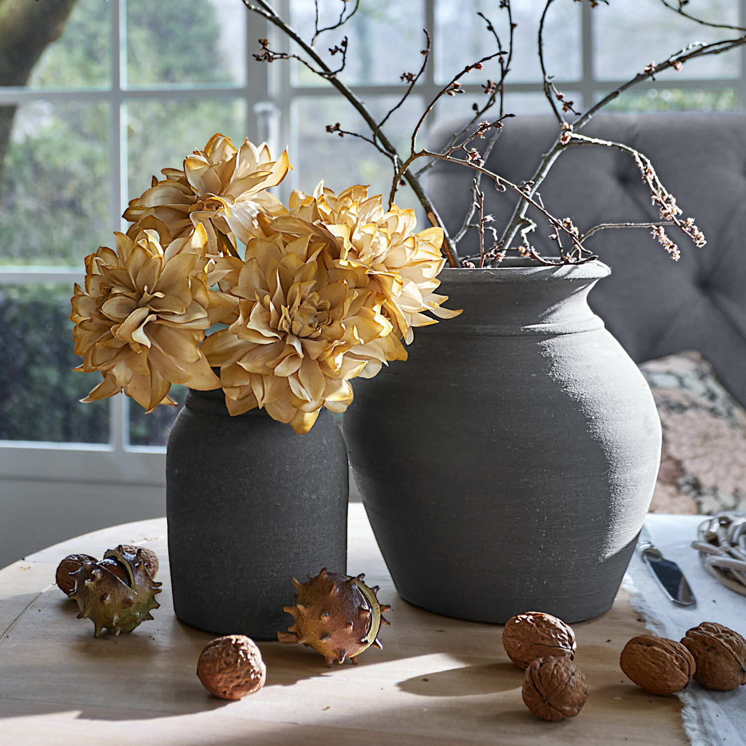 Set di 4 fiori decorativi Cappellina Due vasi in ceramica grigio scuro con fiori secchi e noci su tavolo di legno chiaro