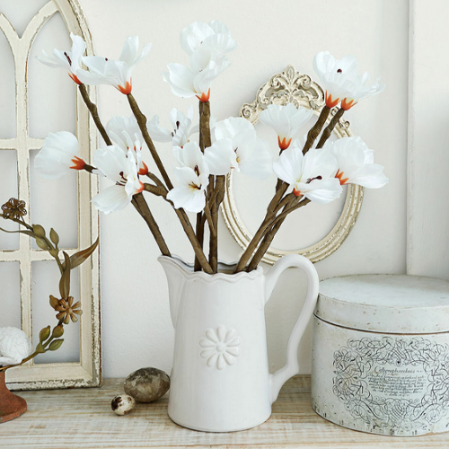 Brocca in ceramica bianca con fiori decorativi su tavolo in legno, stile vintage, decorazione d'interni