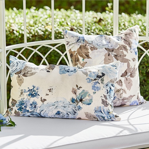 Cuscini decorativi con motivo floreale blu e beige su panca da giardino bianca in metallo