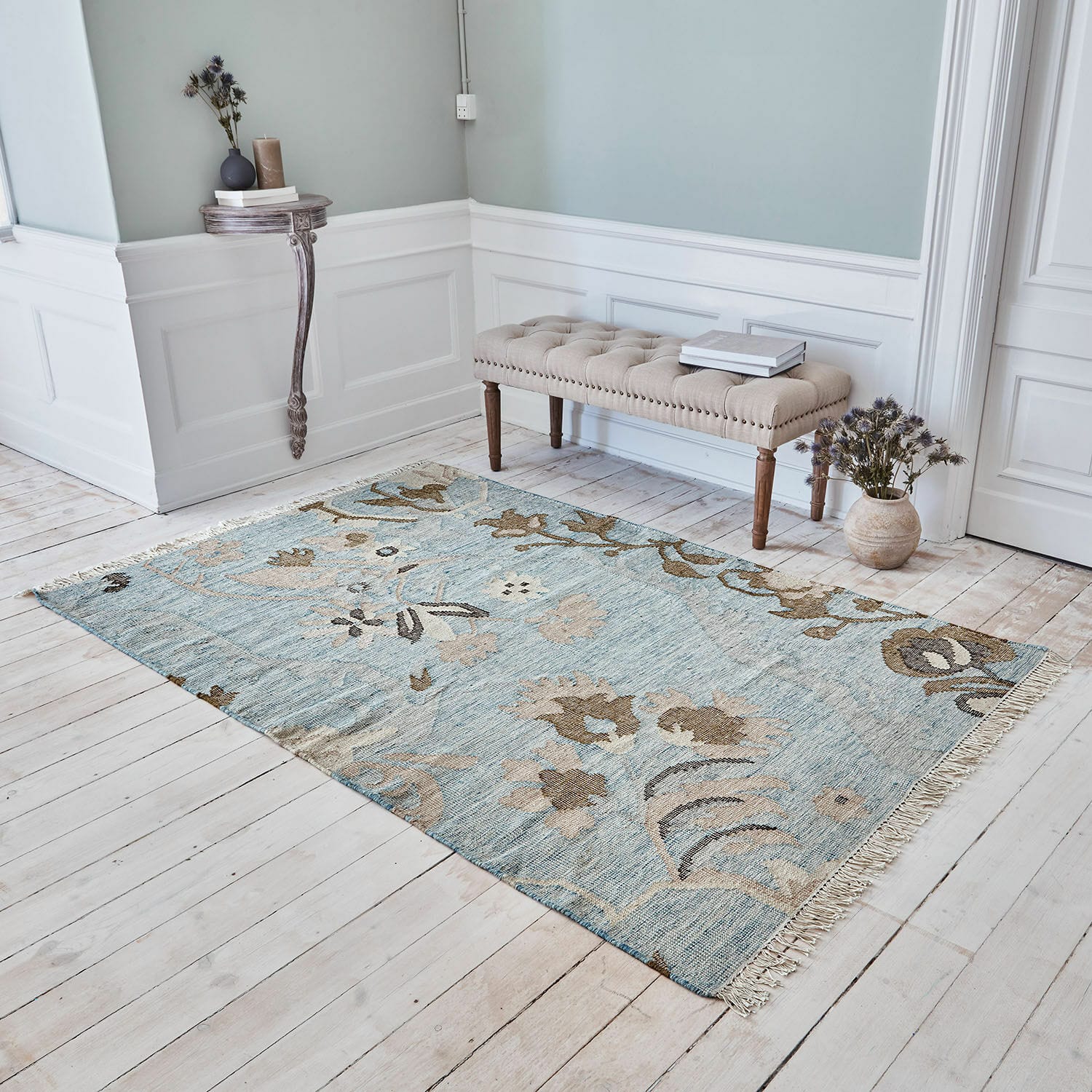 Tappeto Nére Tappeto in cotone azzurro con motivi floreali beige su pavimento in legno chiaro in soggiorno