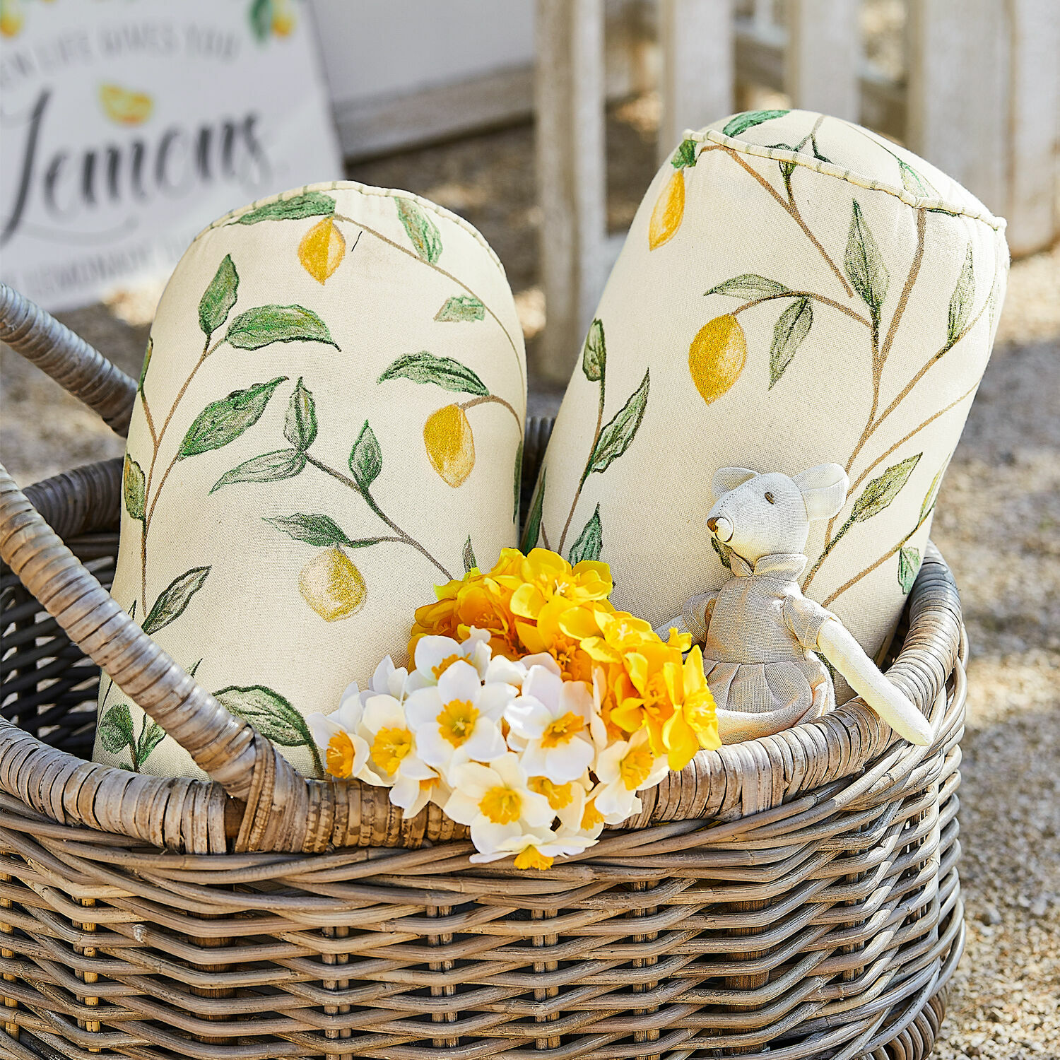 Coppia di cuscini cilindrici Palerina Cuscini decorativi in cotone crema con motivo limoni in cesto di vimini con fiori gialli e bianchi
