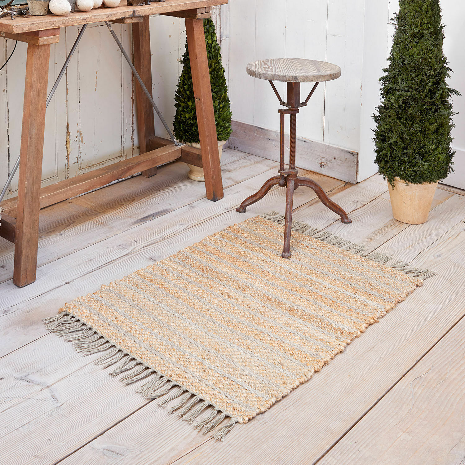 Tappeto Voyage Tappeto in juta beige e grigio a righe con frange su pavimento in legno chiaro, decorazione d'interni