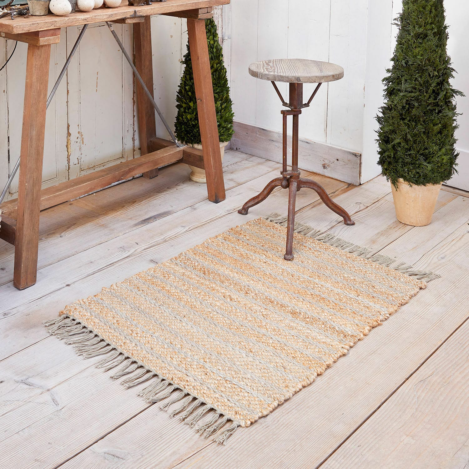 Tappeto Voyage Tappeto in juta beige e grigio a righe con frange su pavimento in legno chiaro, decorazione d'interni