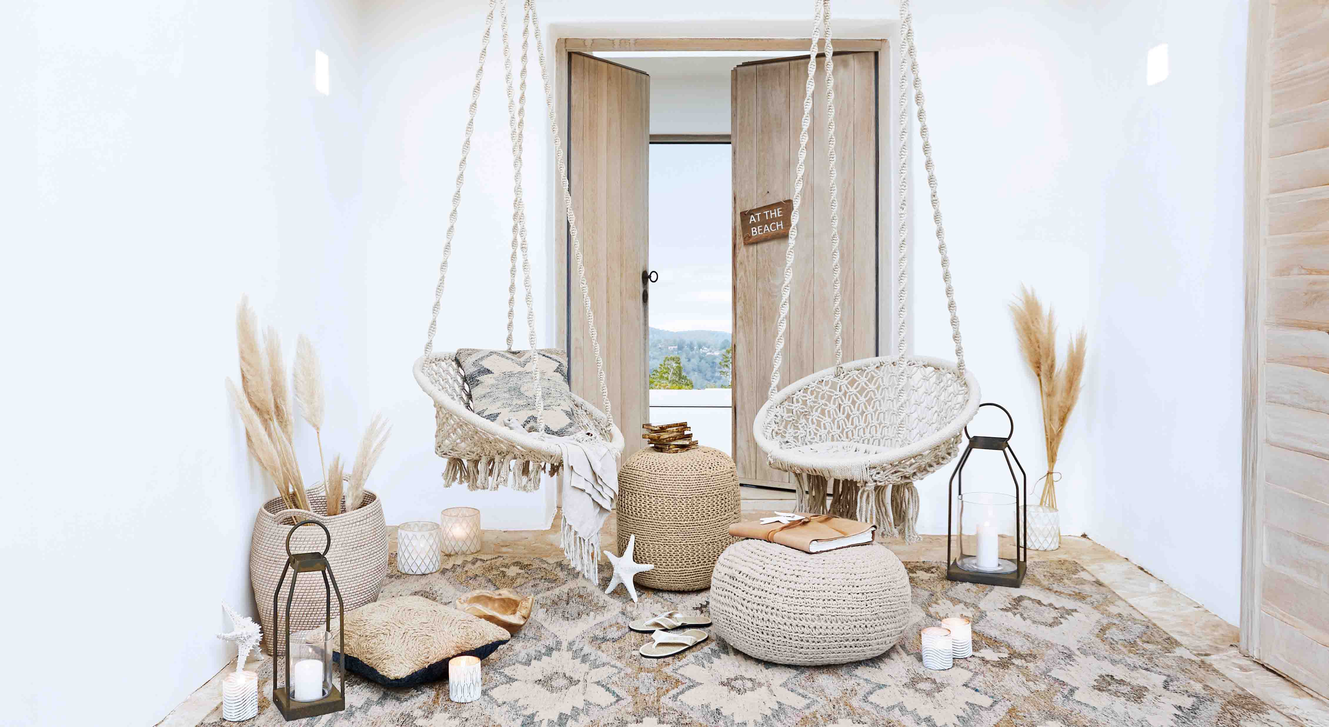 Soggiorno accogliente con sedie sospese in macramè bianco e decorazioni naturali in stile boho