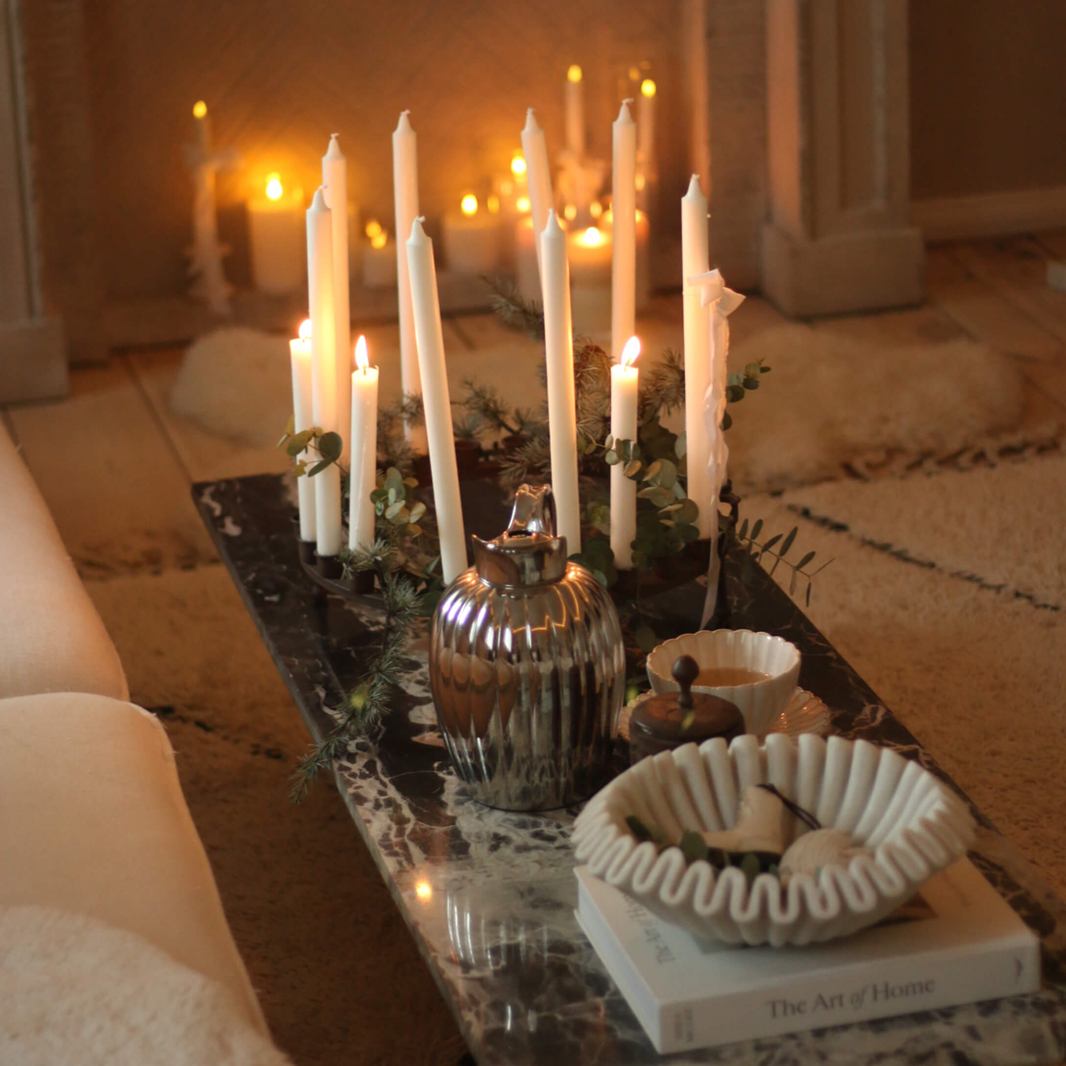Portacandele decorativo con candele bianche su tavolo in marmo con ciotola in ceramica e brocca metallica