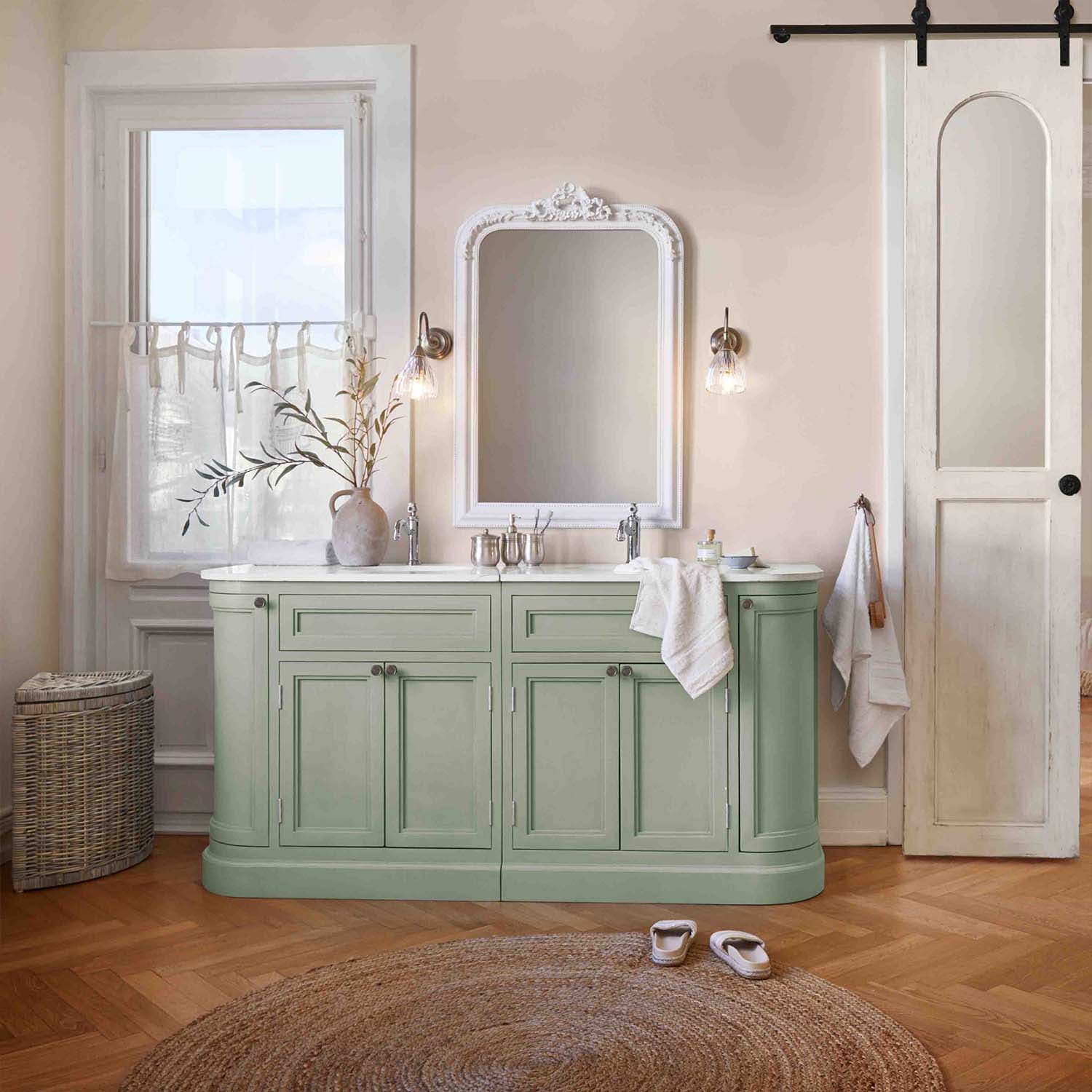 Mobile bagno verde con piano bianco e specchio vintage in ambiente naturale e delicato