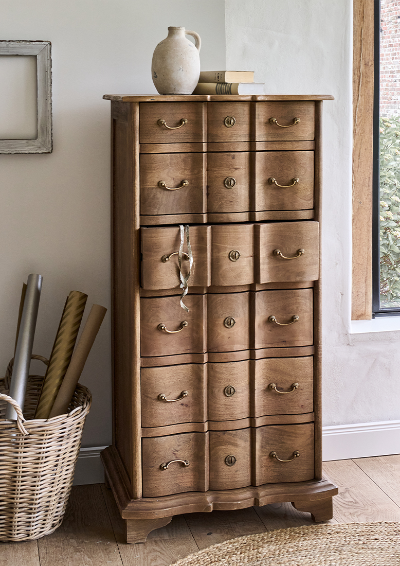 Cassettiera in legno naturale con sei cassetti e maniglie in ottone in ambiente luminoso