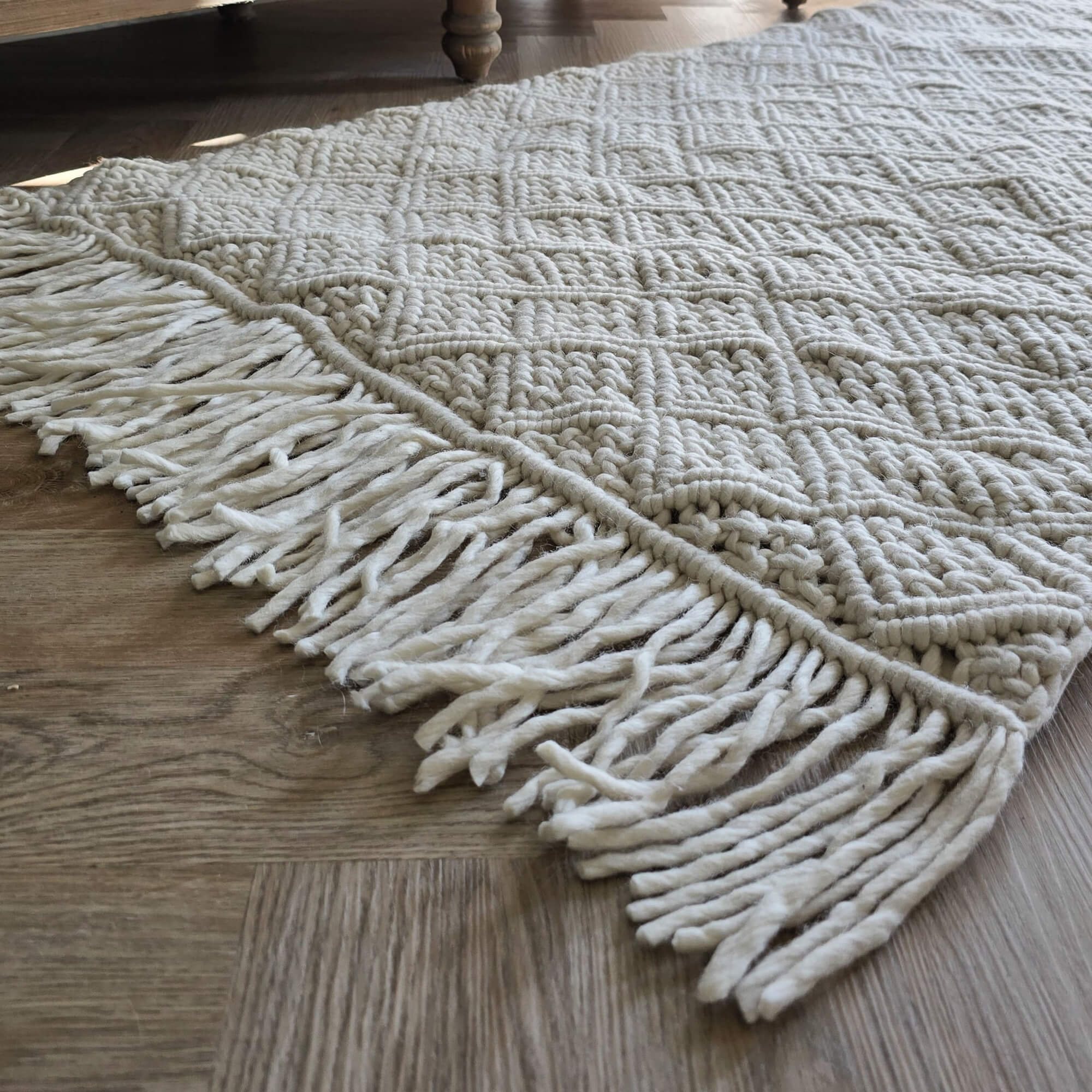 Tappeto bianco con trama spessa e frange su pavimento in legno, decorazione d'interni