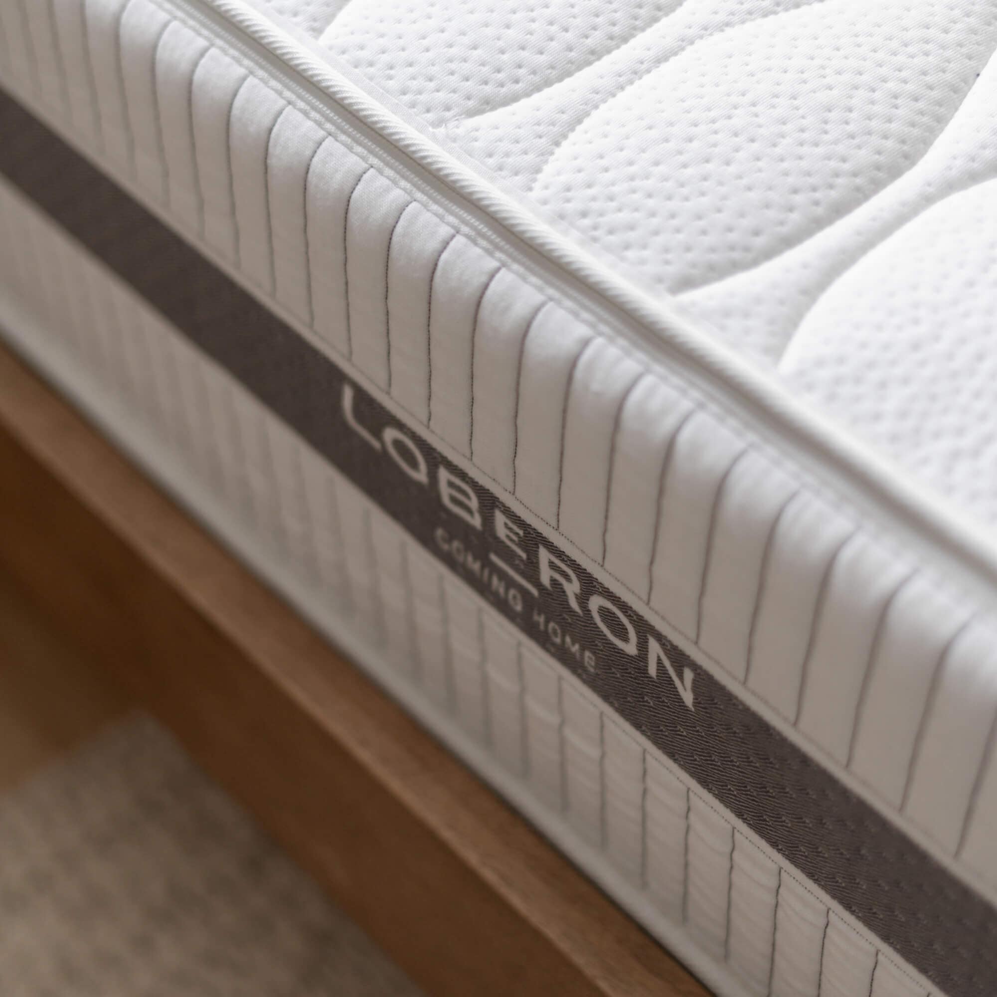 Tessuto trapuntato bianco del materasso con bordo grigio su struttura letto in legno