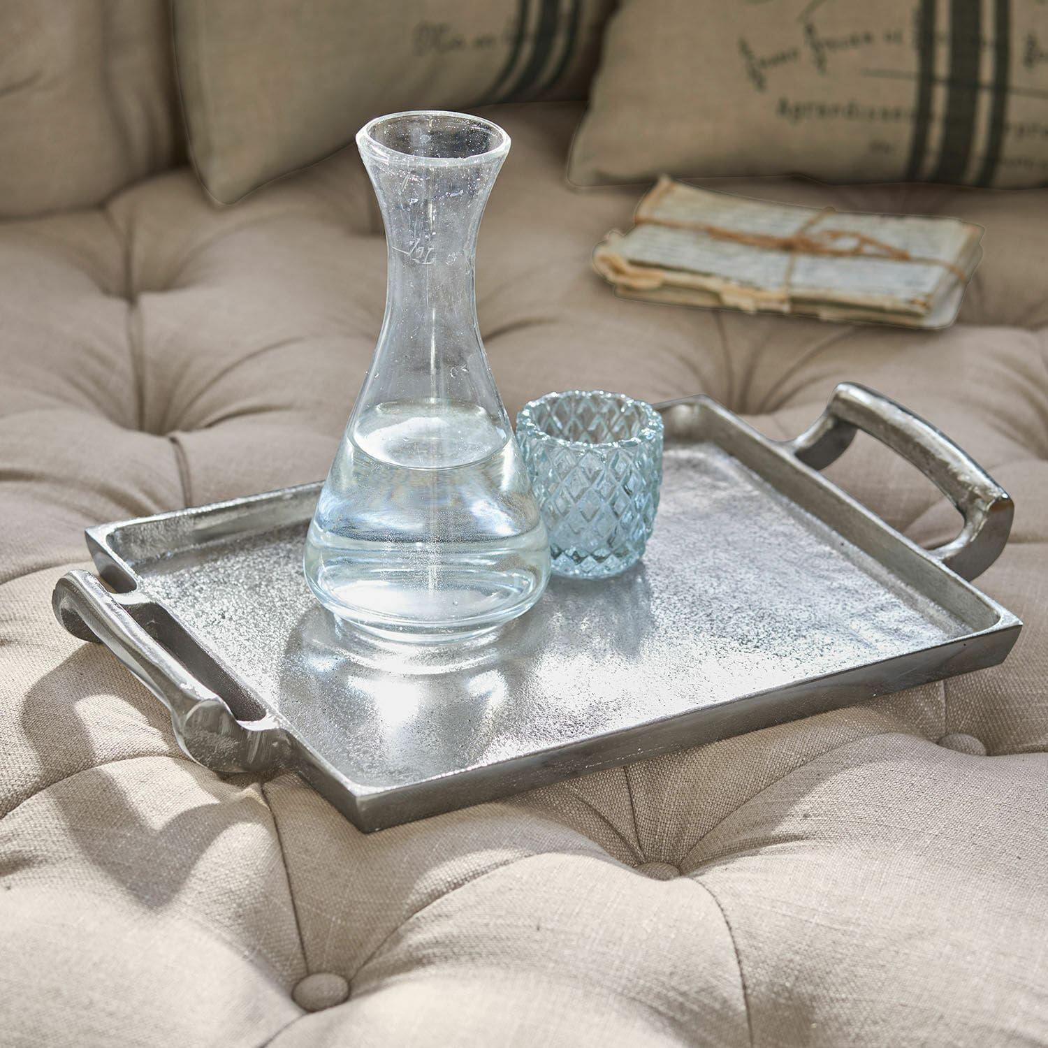 Vassoio Connaire Vassoio decorativo in metallo argentato su tessuto beige trapuntato con caraffa e bicchiere in vetro