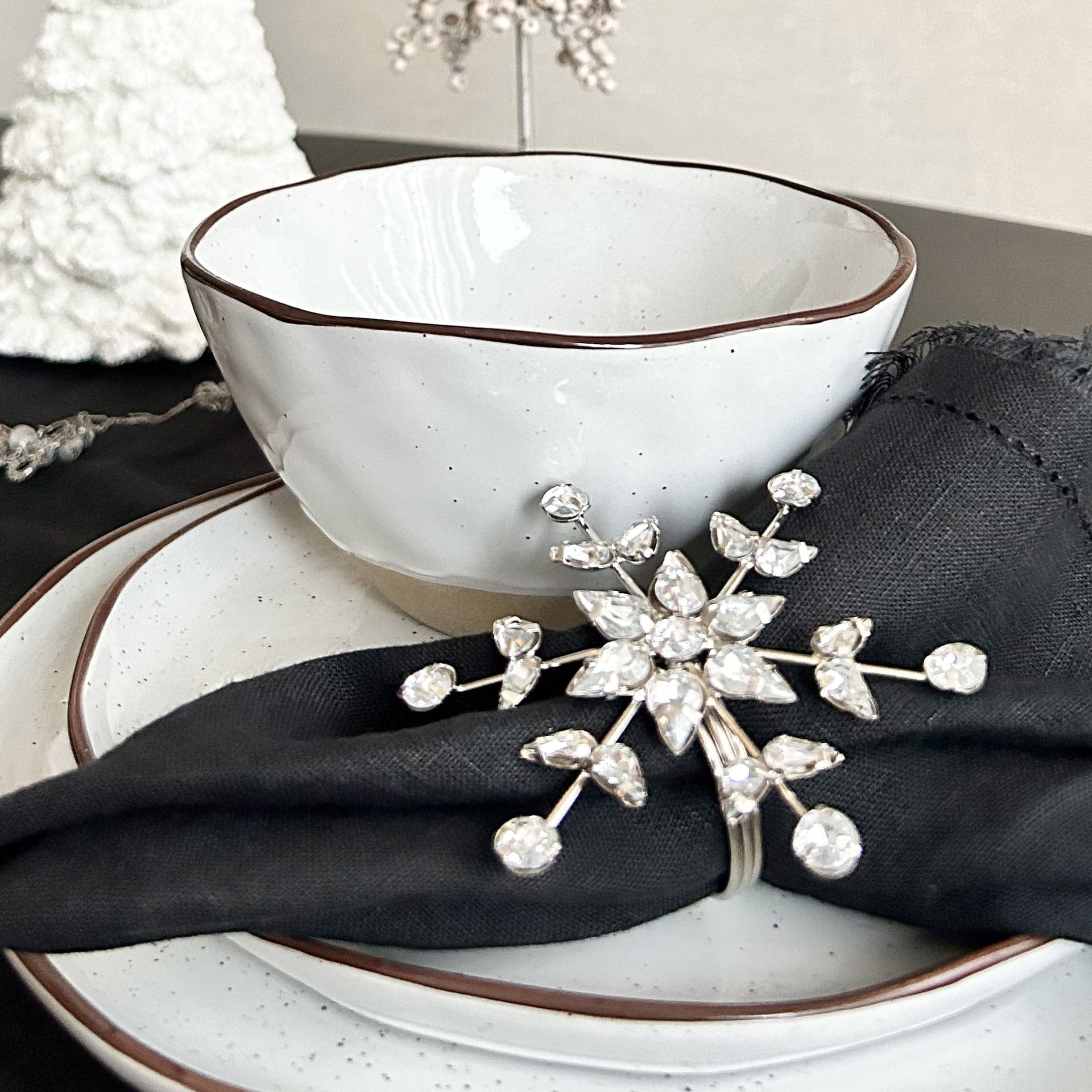 Ciotola e piatto in ceramica bianca con bordo marrone, tovagliolo nero con anello decorativo di cristalli