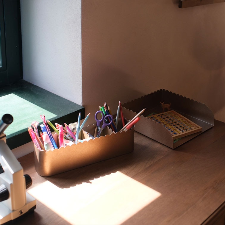 Contenitori da scrivania in metallo marrone con bordi ondulati, pieni di cancelleria e un libro