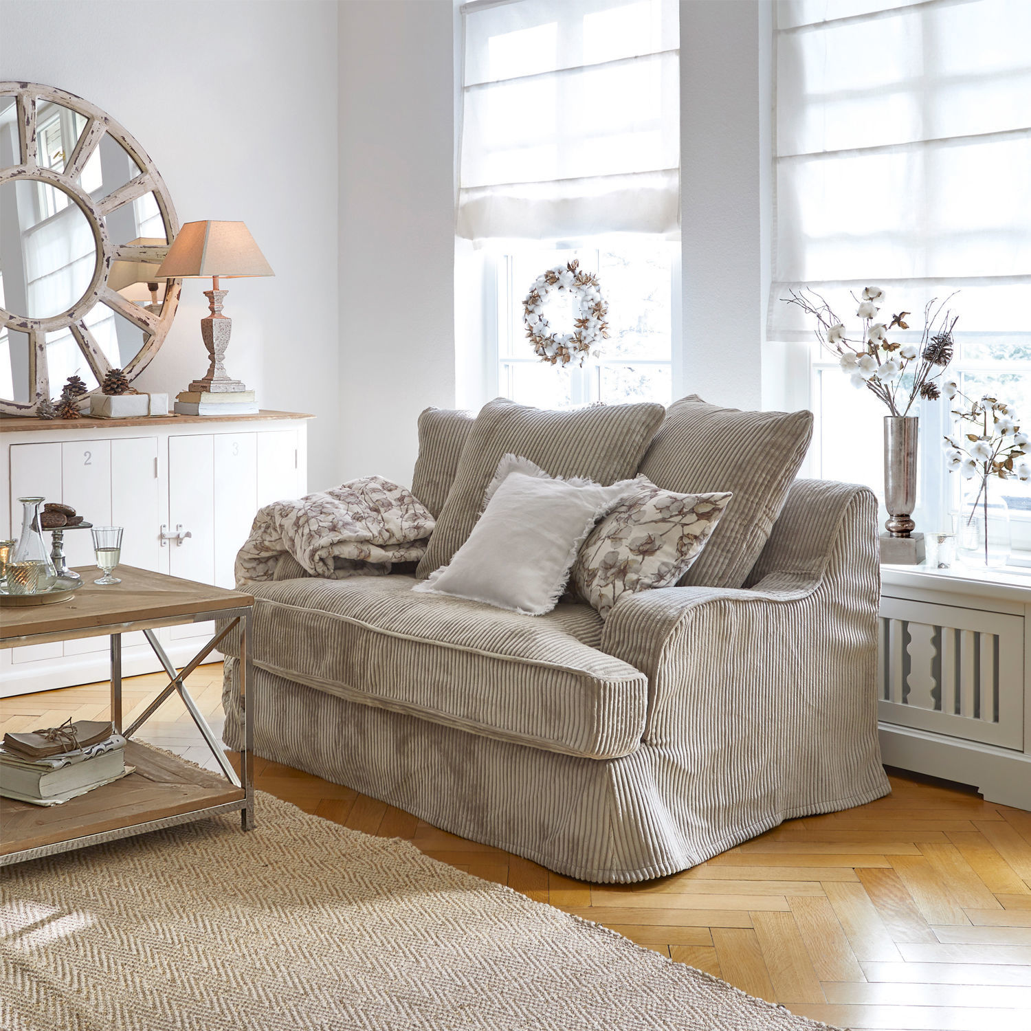 Divano Monaco Divano beige in velluto a coste in soggiorno luminoso con decorazioni naturali e tappeto in juta