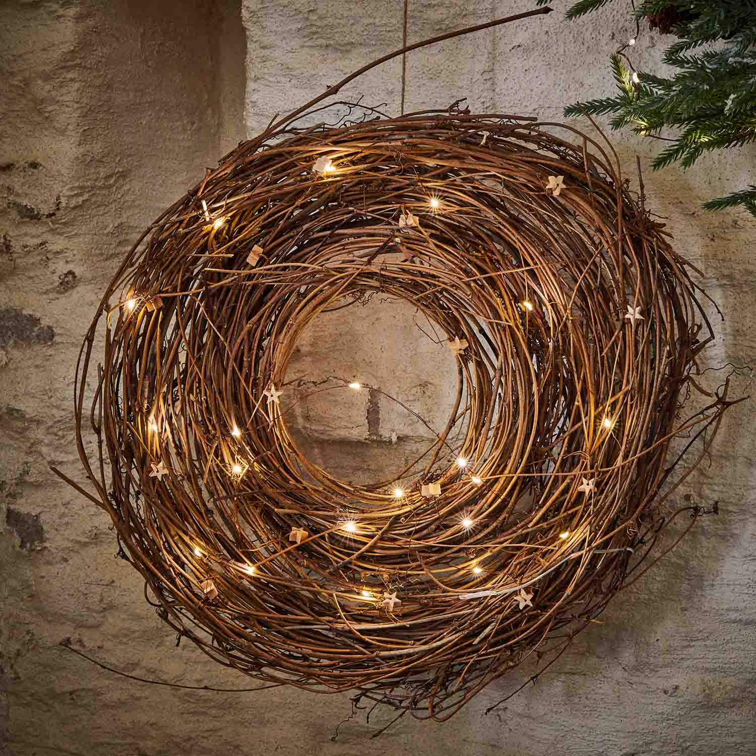 Corona decorativa di rami naturali con luci LED delicate appesa al muro