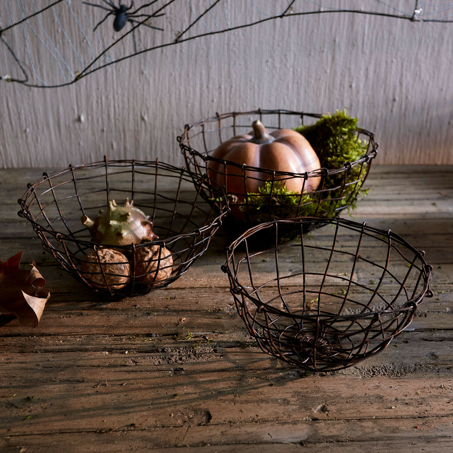 Set di 3 cesti Brannora Set di tre cesti in metallo arrugginito su tavolo di legno con zucca decorativa e noci