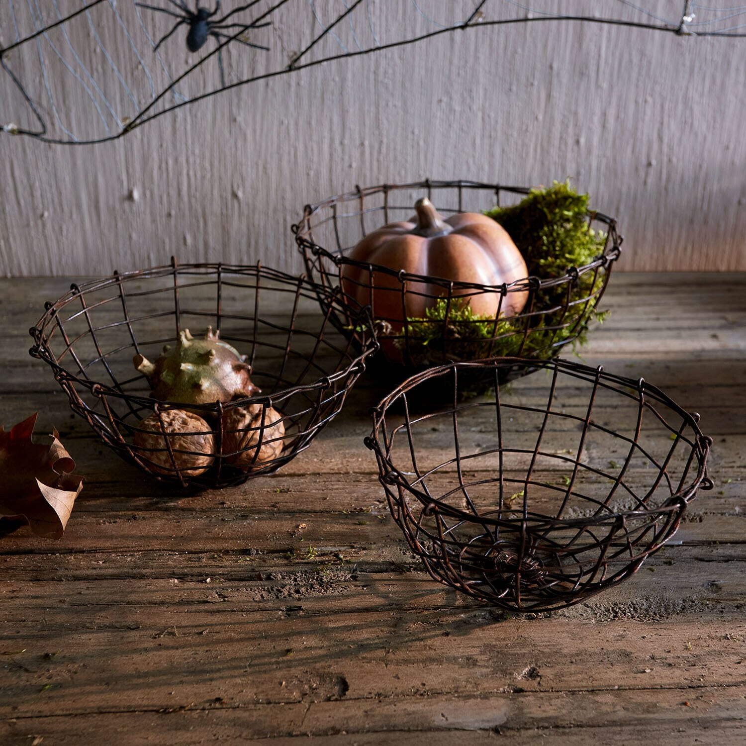 Set di 3 cesti Brannora Set di tre cesti in metallo arrugginito su tavolo di legno con zucca decorativa e noci