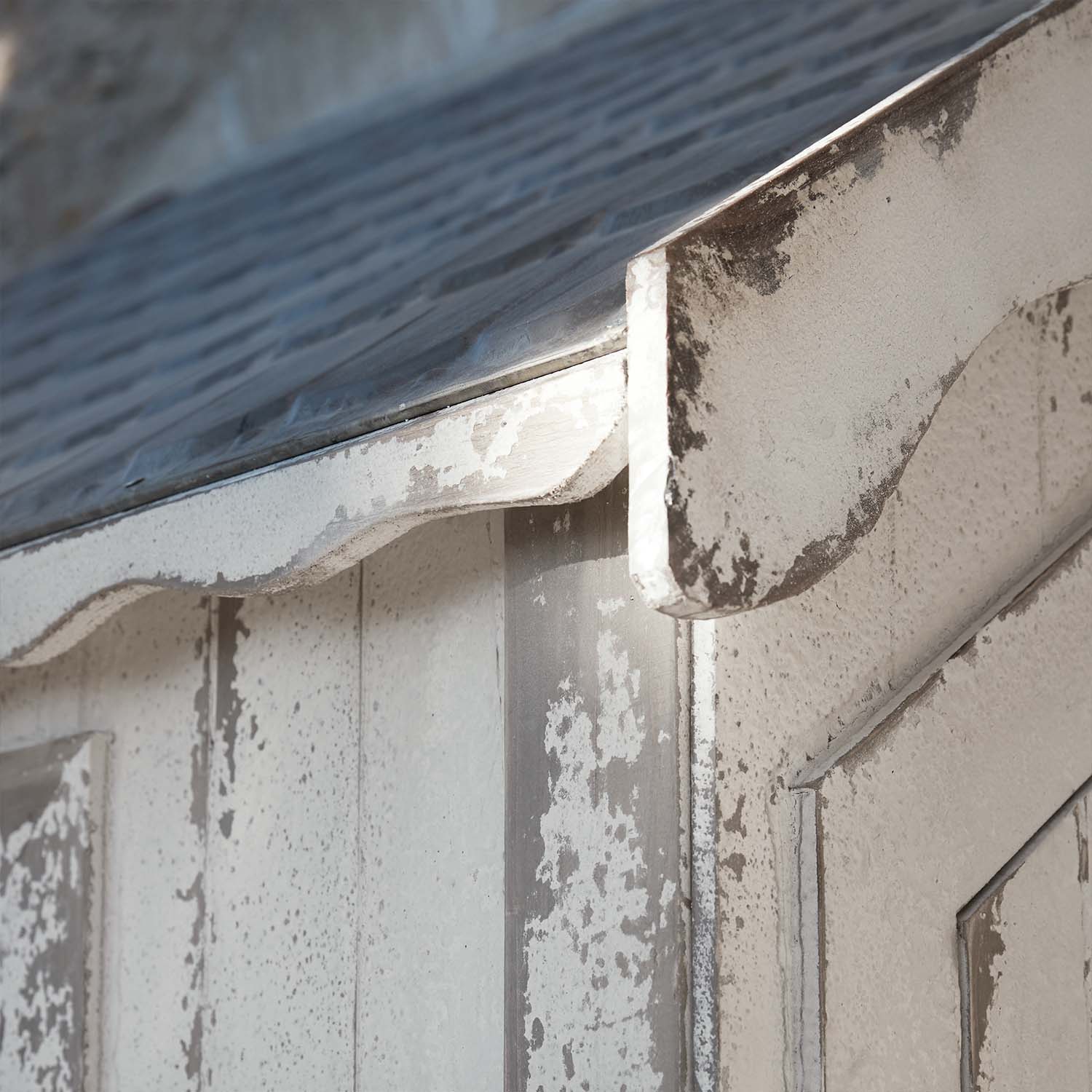 Primo piano di struttura in legno bianco invecchiato con tetto in metallo e bordo curvo