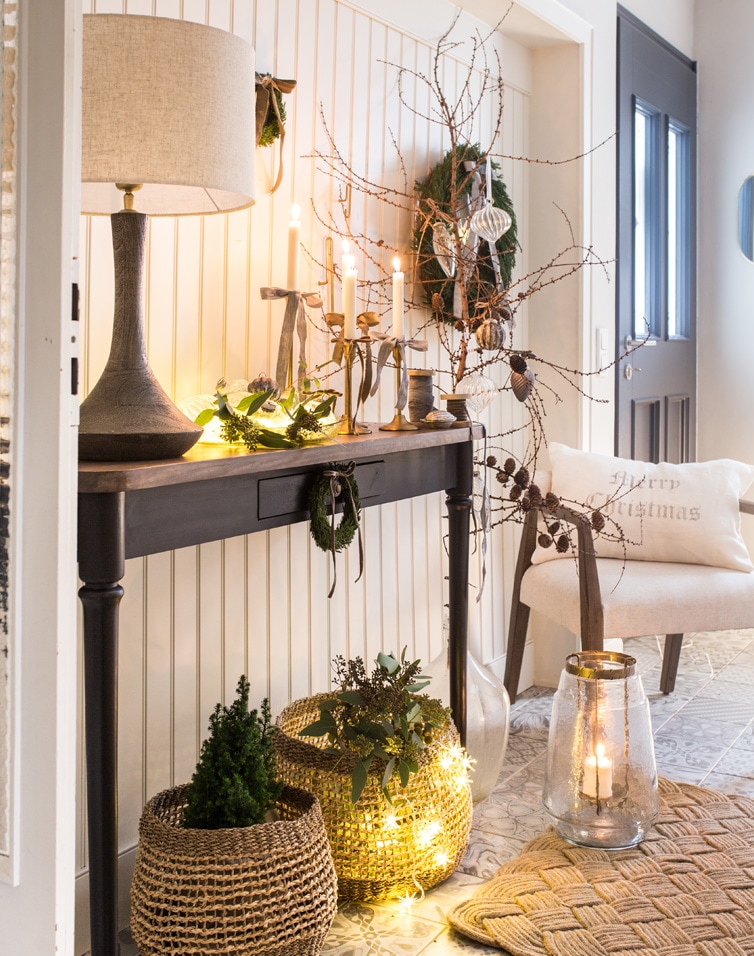 Accogliente decorazione natalizia con tavolo nero, lampada e decorazioni naturali nell'ingresso