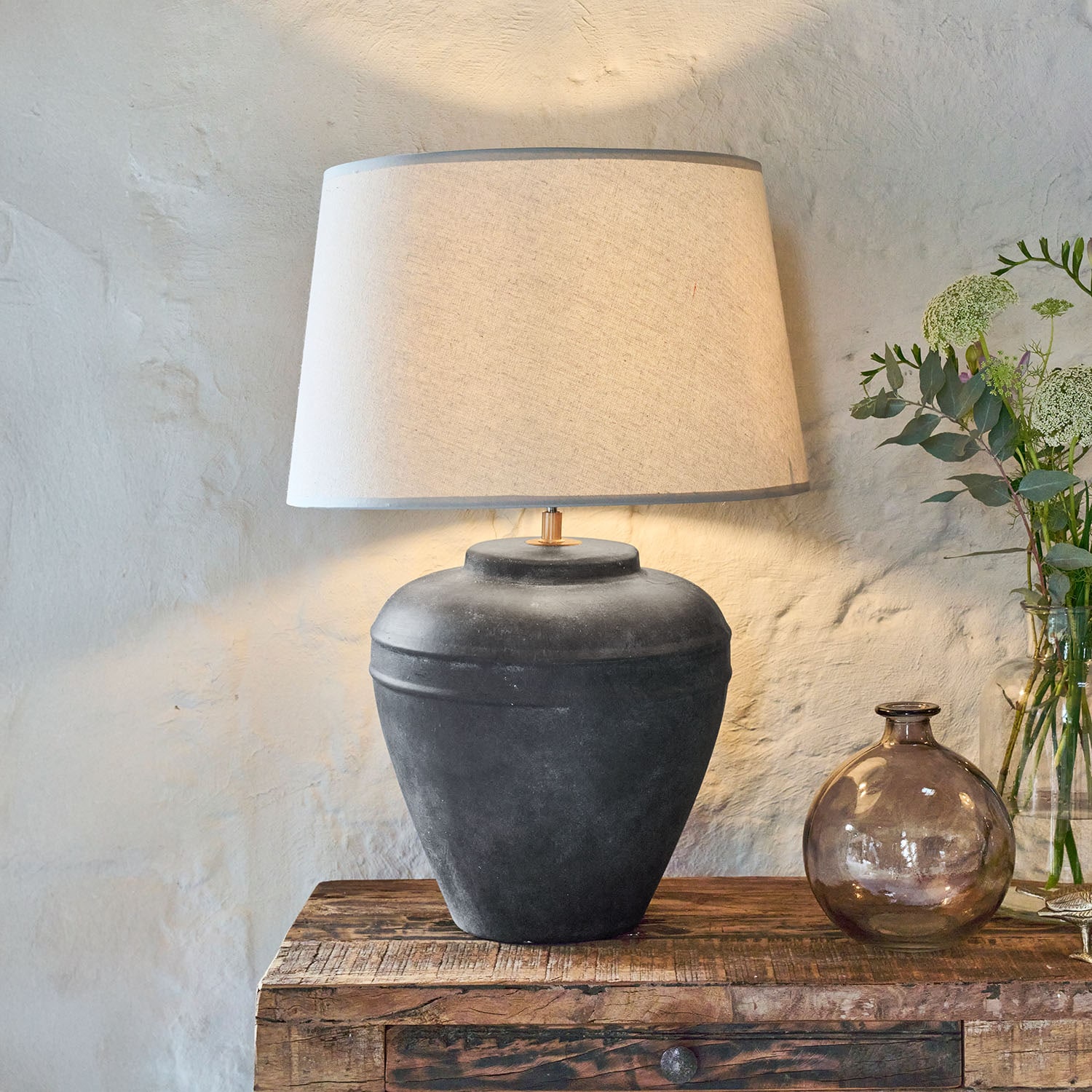 Lampada da tavolo in ceramica nera con paralume beige su tavolo in legno rustico